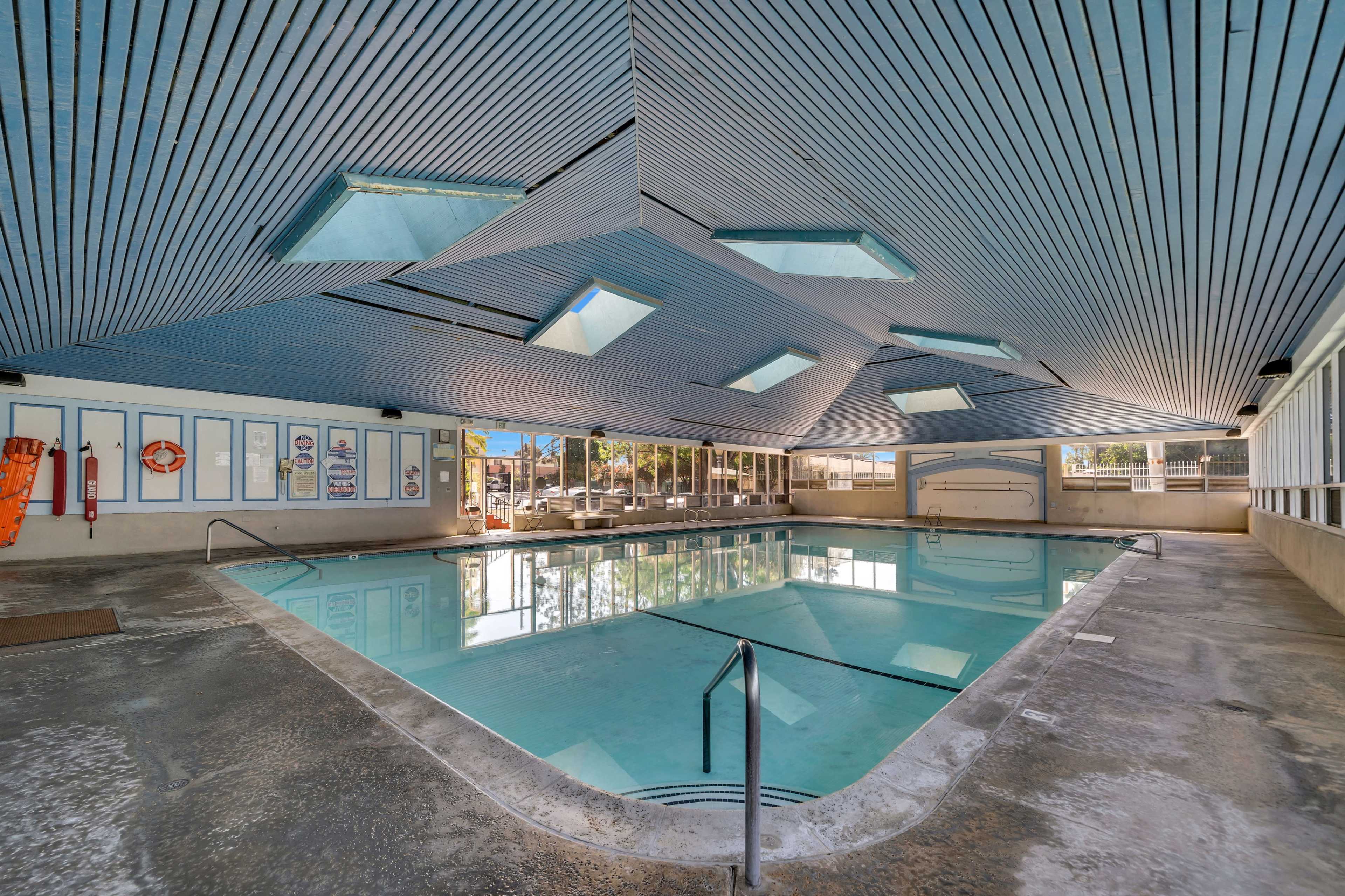 An indoor swimming pool with a geometric ceiling and several skylights overhead.