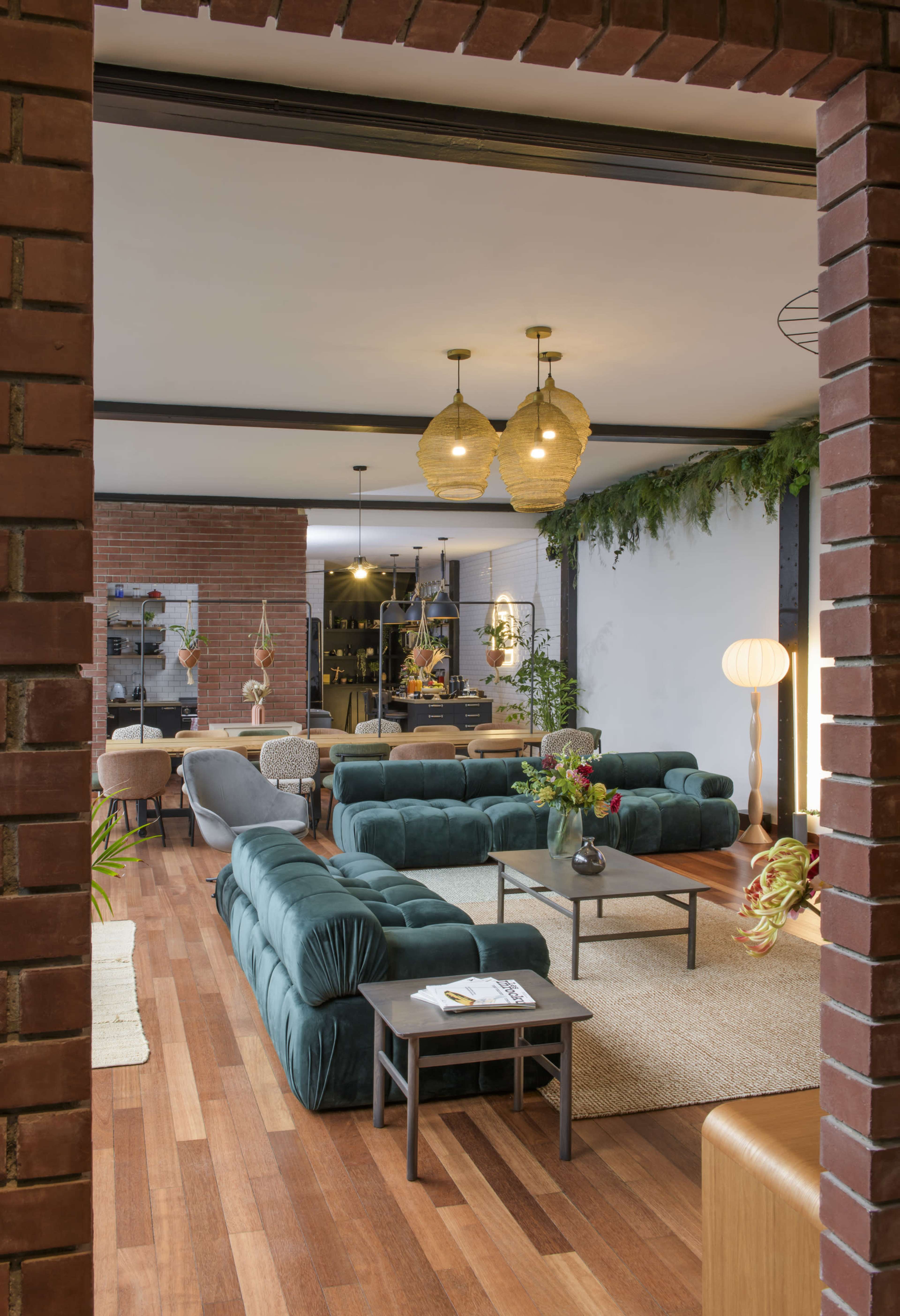The image shows a modern living room with teal sofas, wooden flooring, and decorative plants, visible through a brick archway.