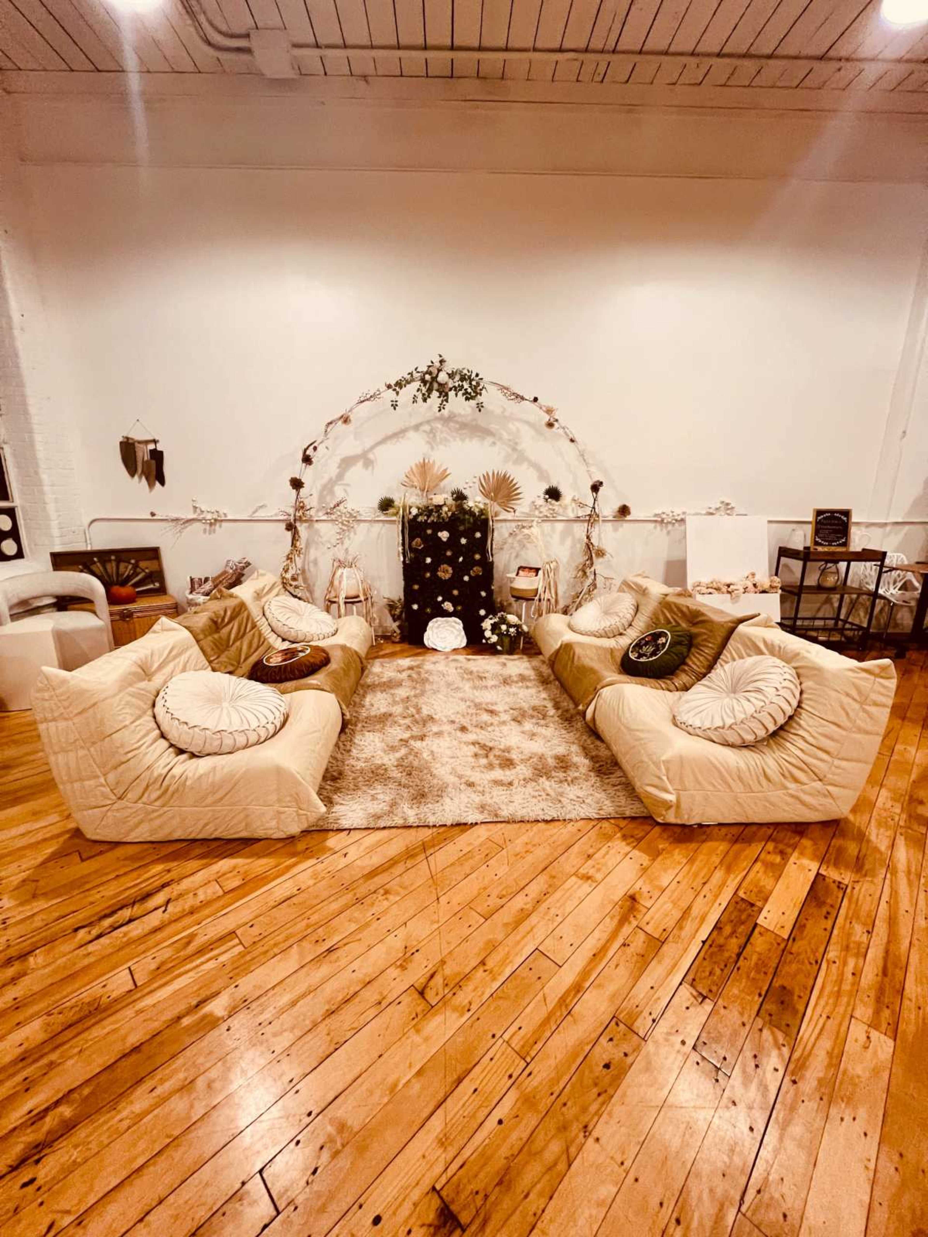 The image shows a cozy seating arrangement with two large, upholstered sofas facing a decorative backdrop in a spacious room with hardwood floors.