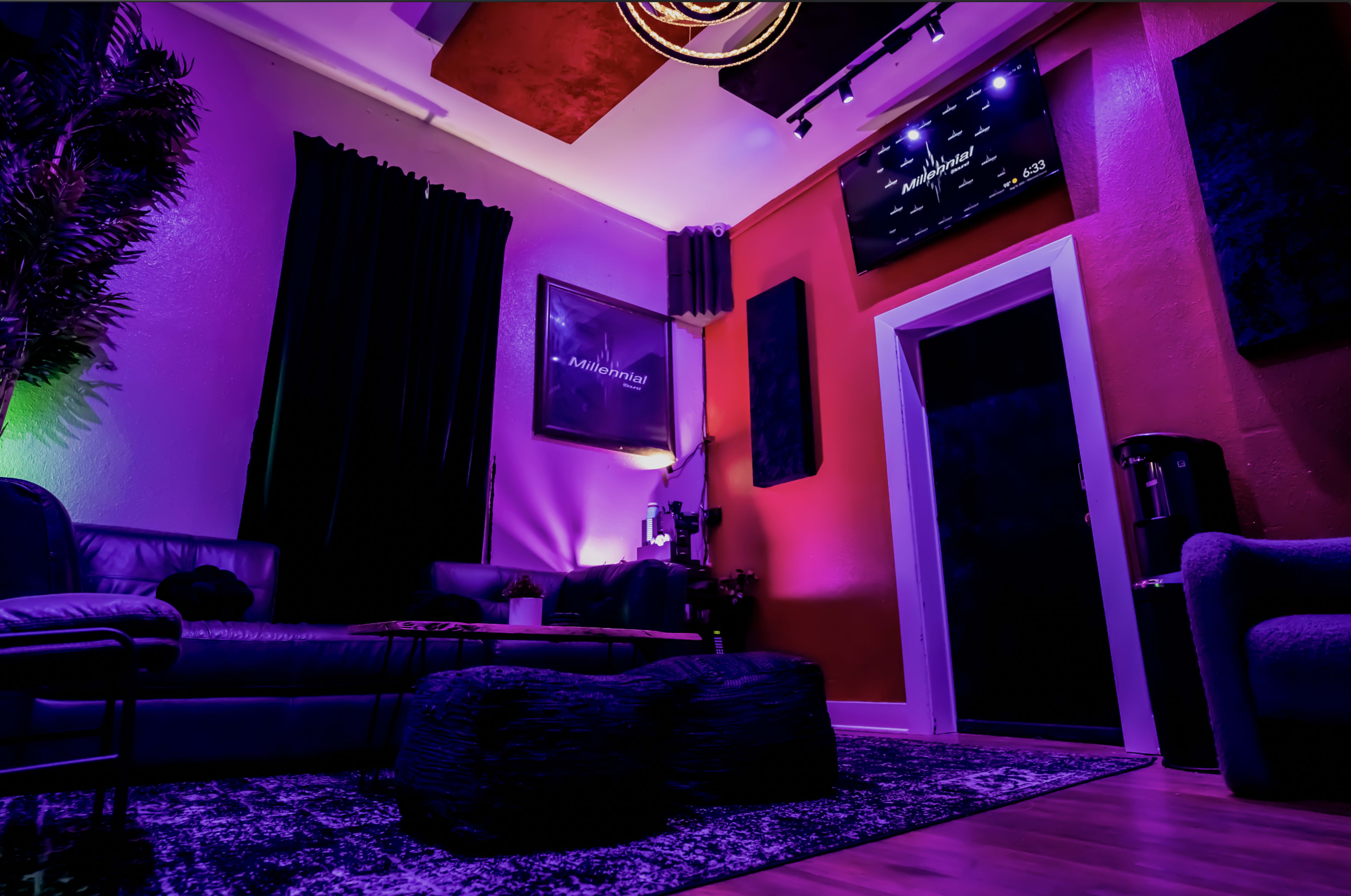 A lounge area features a dark sofa and round coffee table under a colorful illuminated ceiling with artwork on the walls.