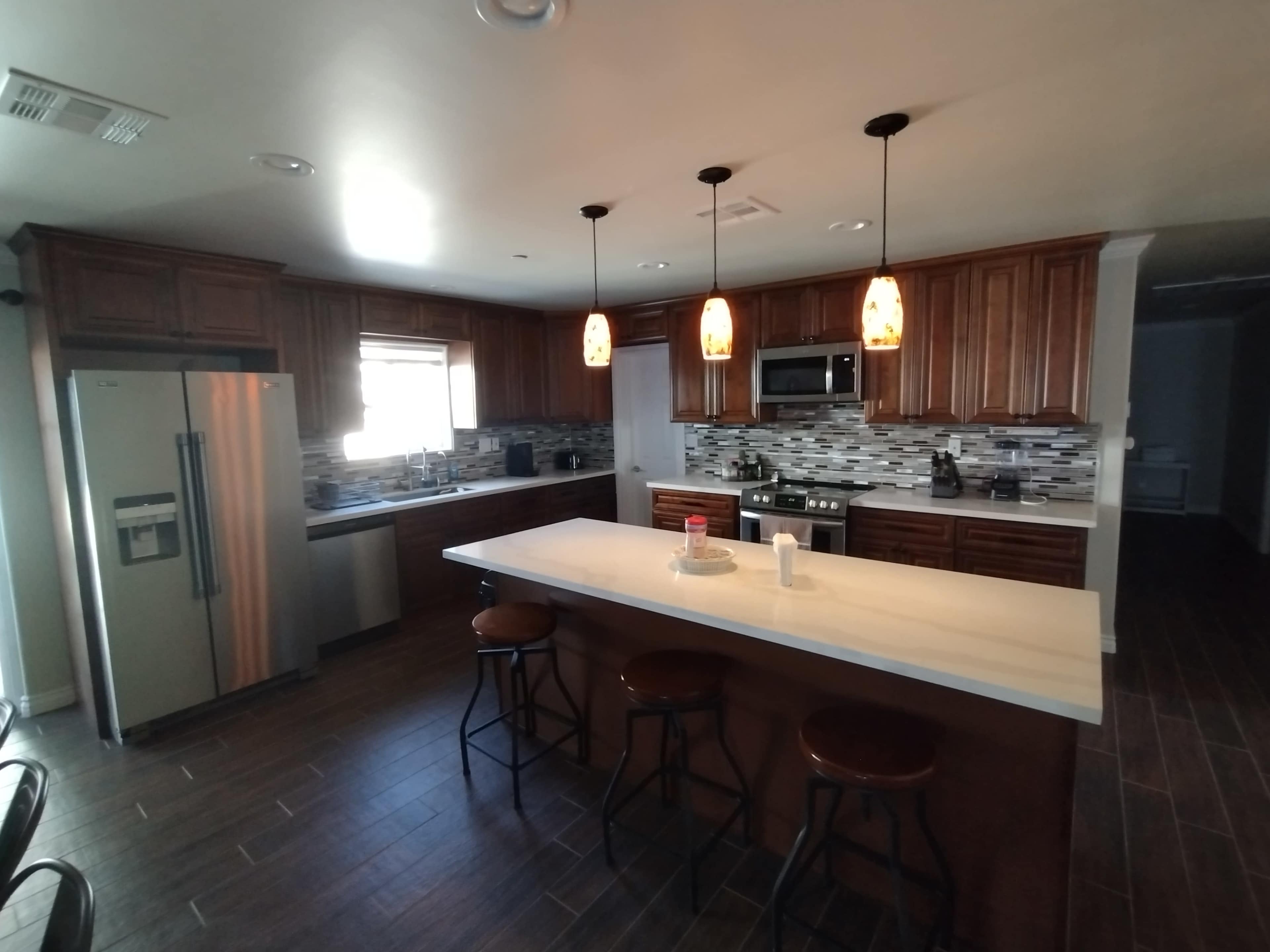 A modern kitchen with wooden cabinets, a central island, and stainless steel appliances.