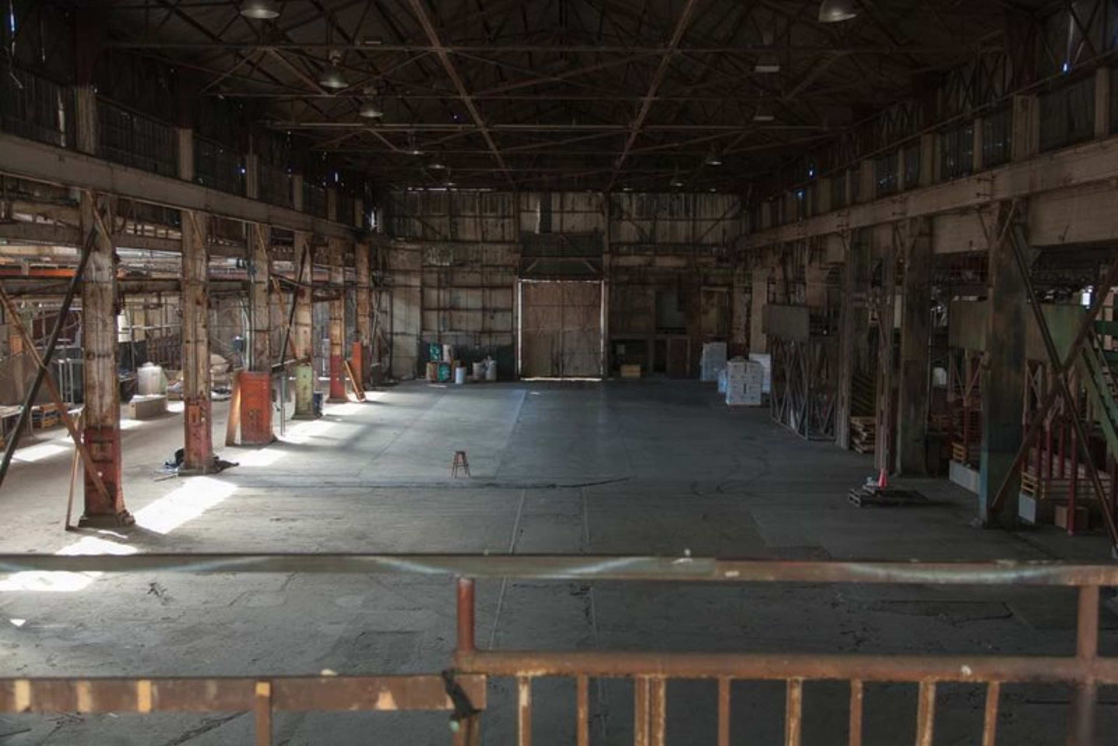 A large, empty industrial warehouse with exposed beams and a concrete floor.