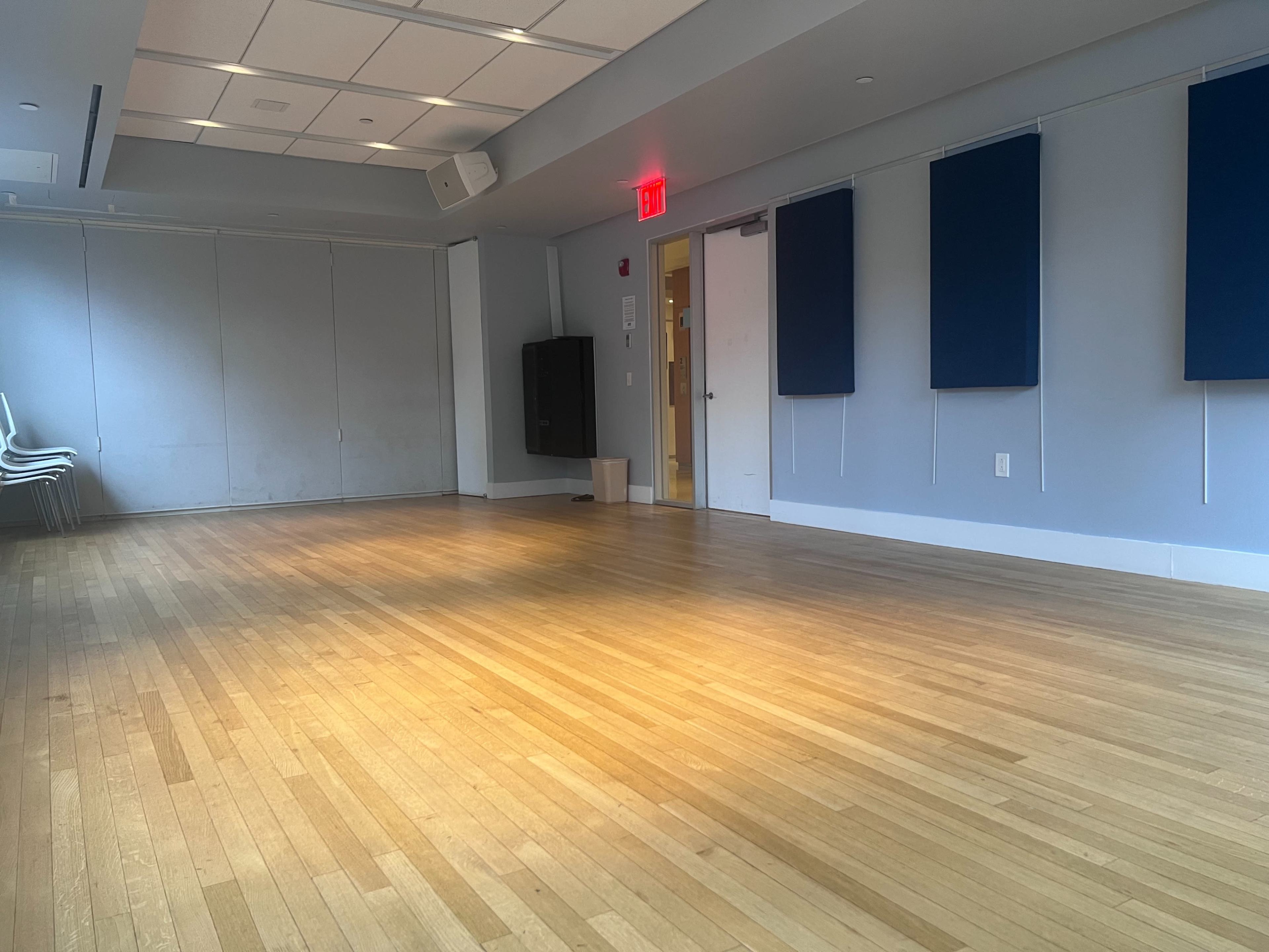 The image shows an empty, well-lit room with hardwood flooring and blue wall panels.