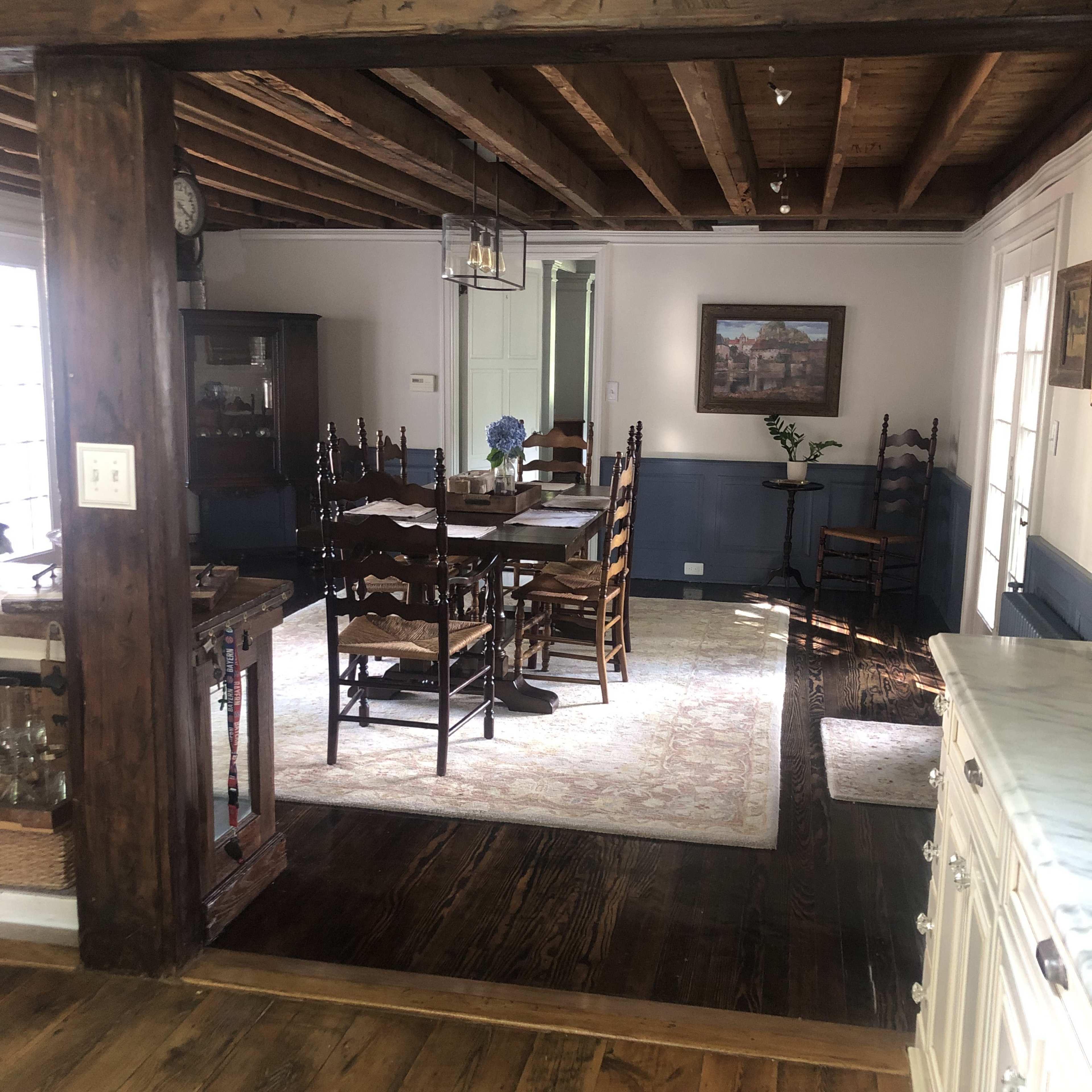 A rustic dining area with a wooden table surrounded by chairs, a light fixture hanging from the ceiling, and a combination of wood and painted walls.