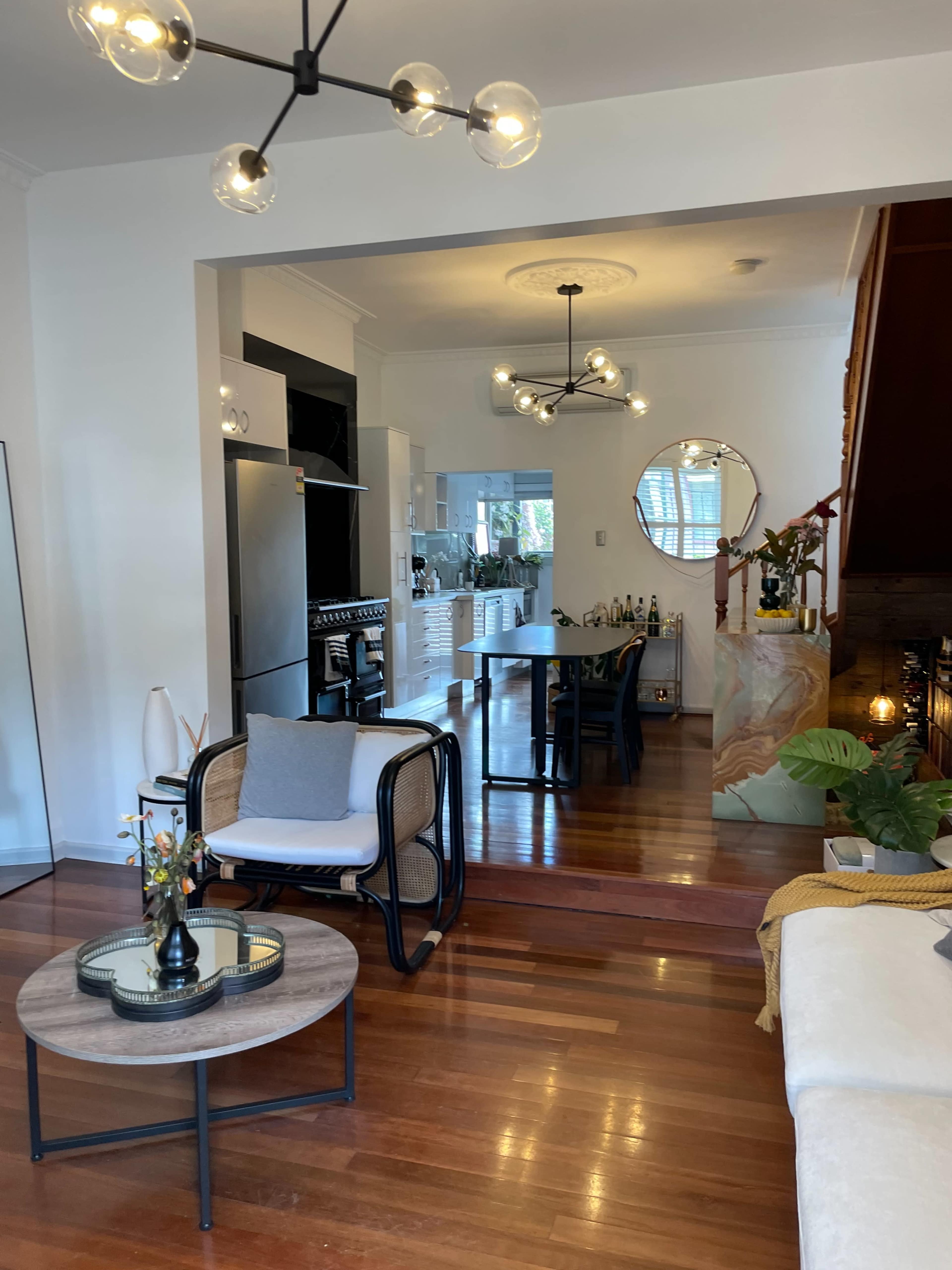 A modern living space with a seating area, a dining table in the background, and a kitchen visible through an open layout.