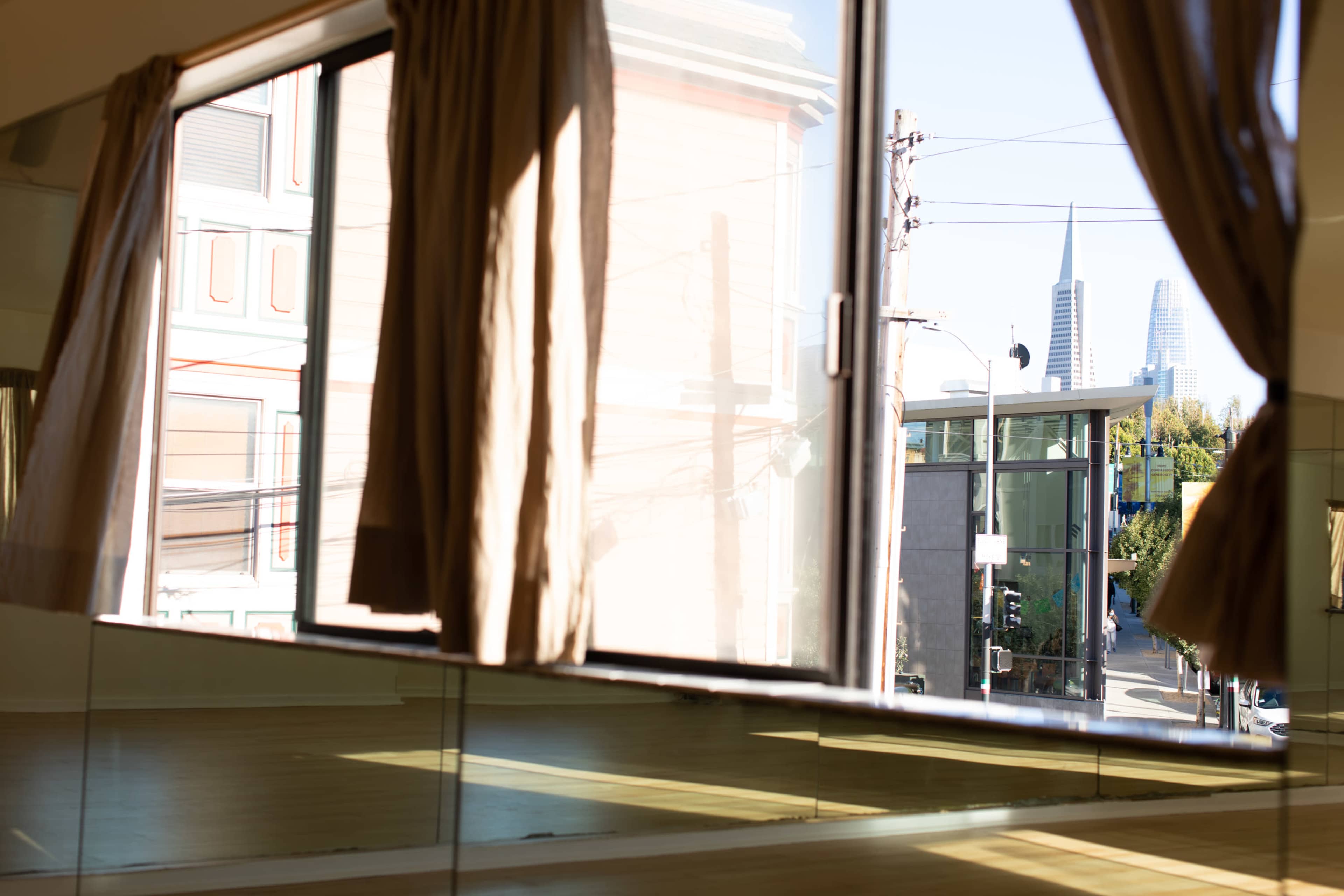 A large window with sheer curtains shows a street view of buildings and distant towers.