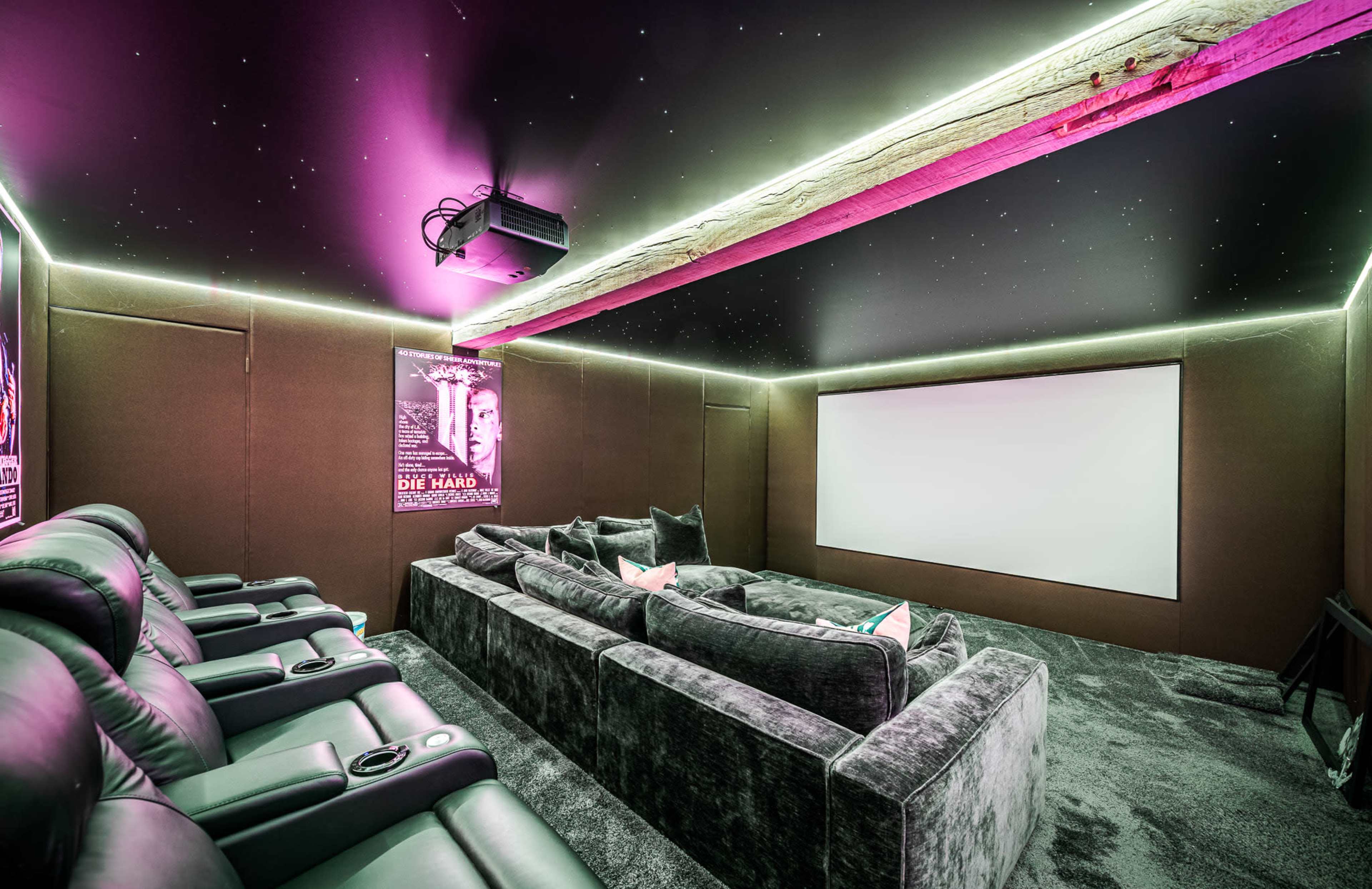 The image shows a modern home theater featuring plush seating, a large projection screen, and ambient lighting with a starry ceiling.