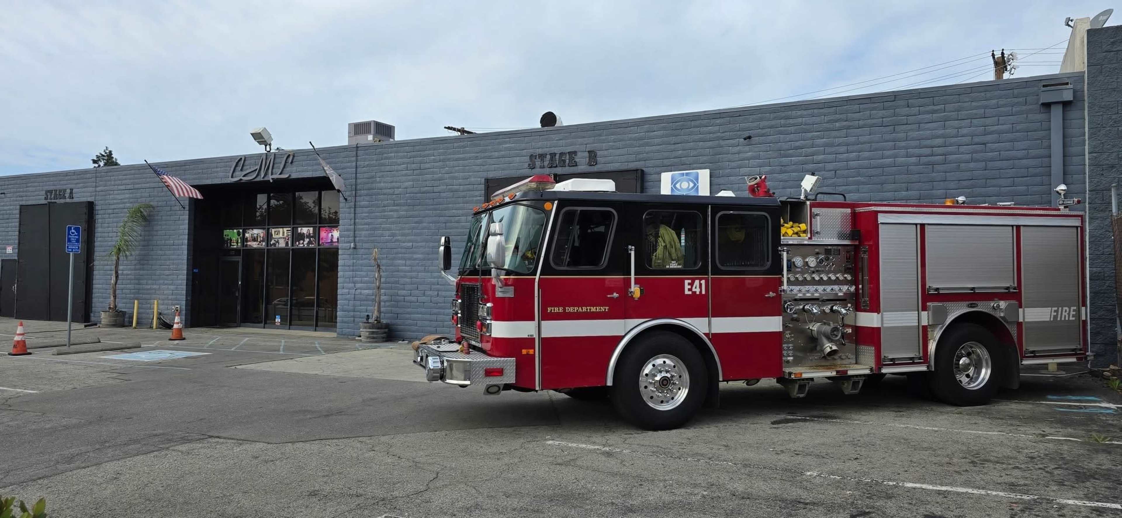 A red fire truck is parked in front of a building with a sign that reads "E41," while an American flag is displayed above the entrance.