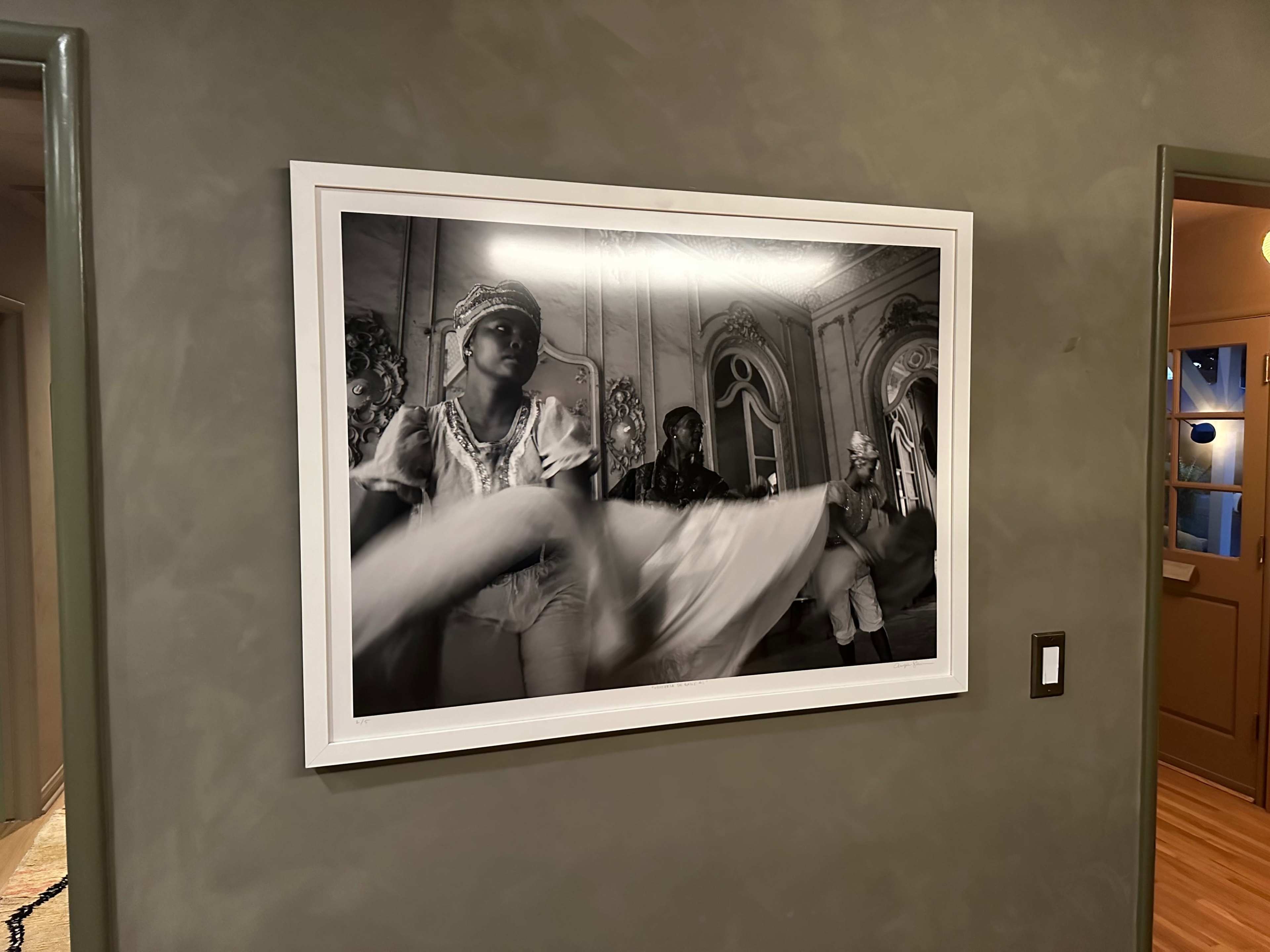 The image features a black and white photograph of performers preparing for a theatrical production, with one figure prominently tossing draped fabric.