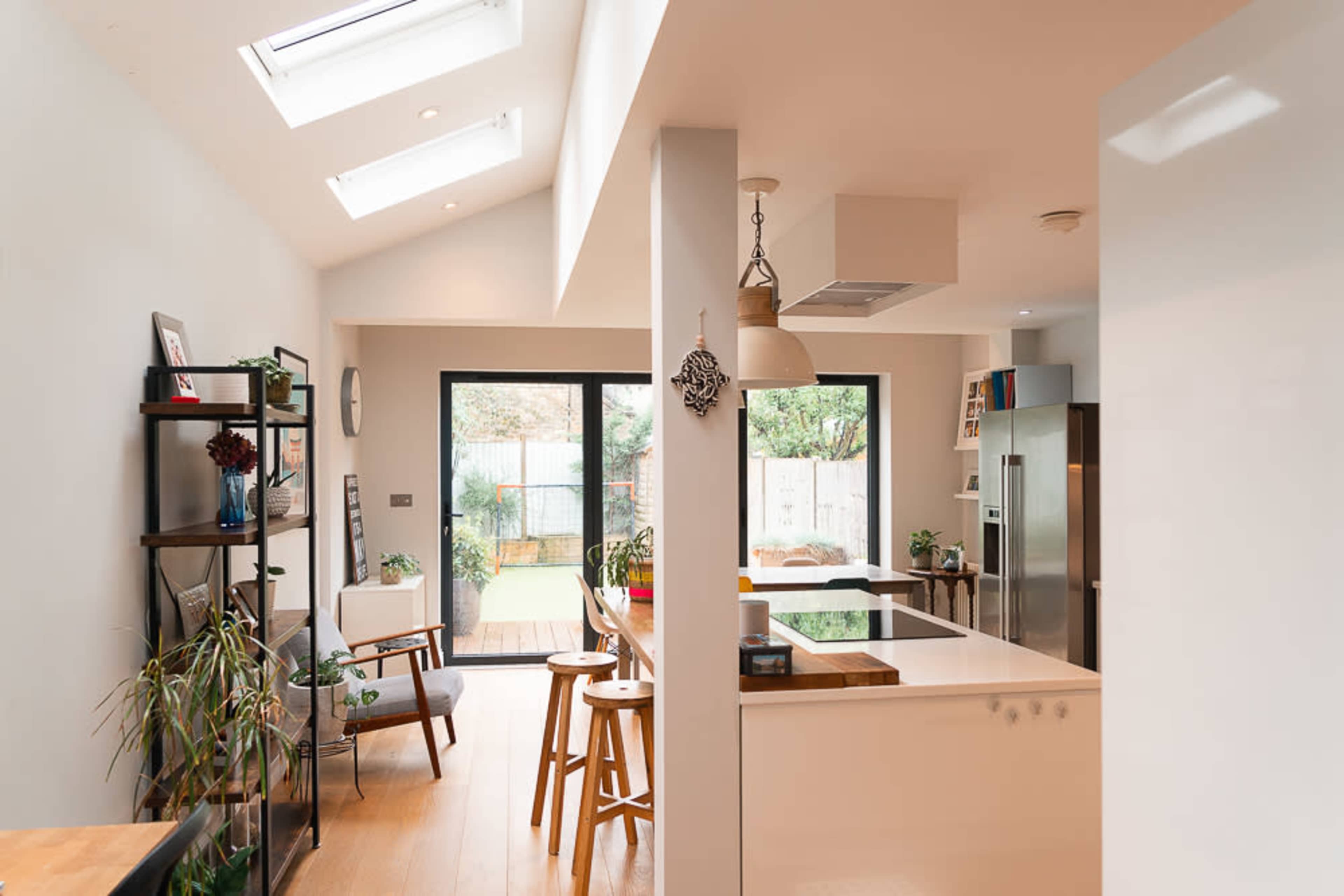 A modern kitchen and dining area with large windows, skylights, and a view of an outdoor patio.