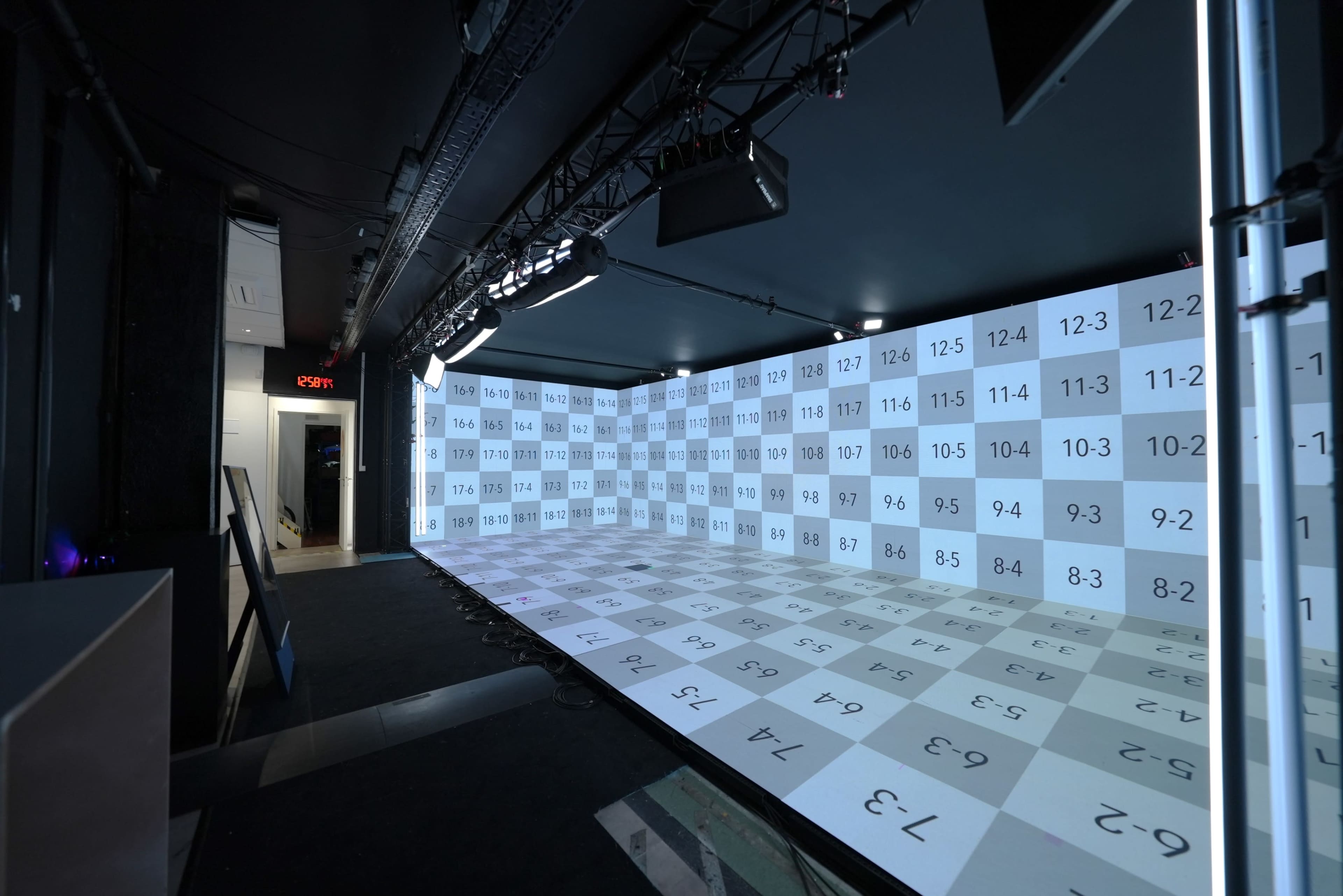The image shows a large, immersive projection area with a grid of numbers displayed across the floor and walls in a dark room.