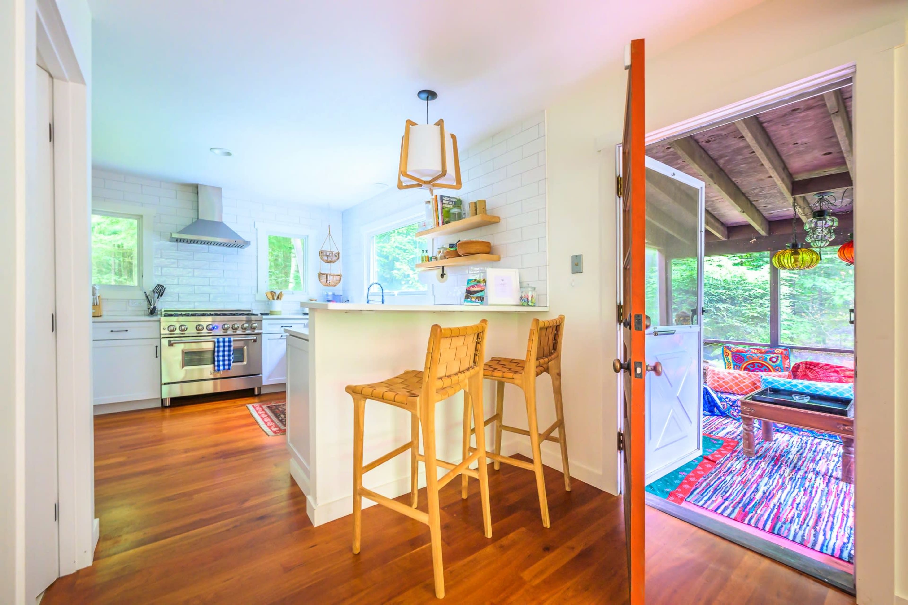 A modern kitchen features white cabinetry, stainless steel appliances, and a door opening to a cozy outdoor seating area.
