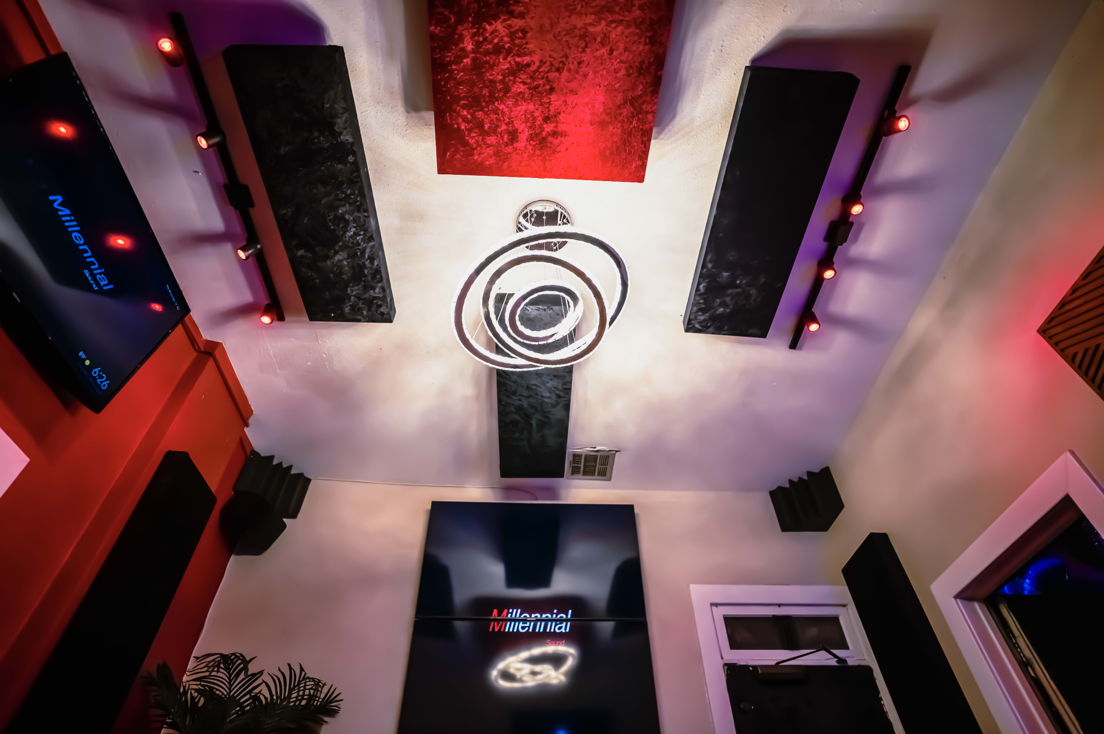 A modern room with a distinctive ceiling design featuring circular light fixtures, sound panels, and a large screen displaying the word "Millennial."