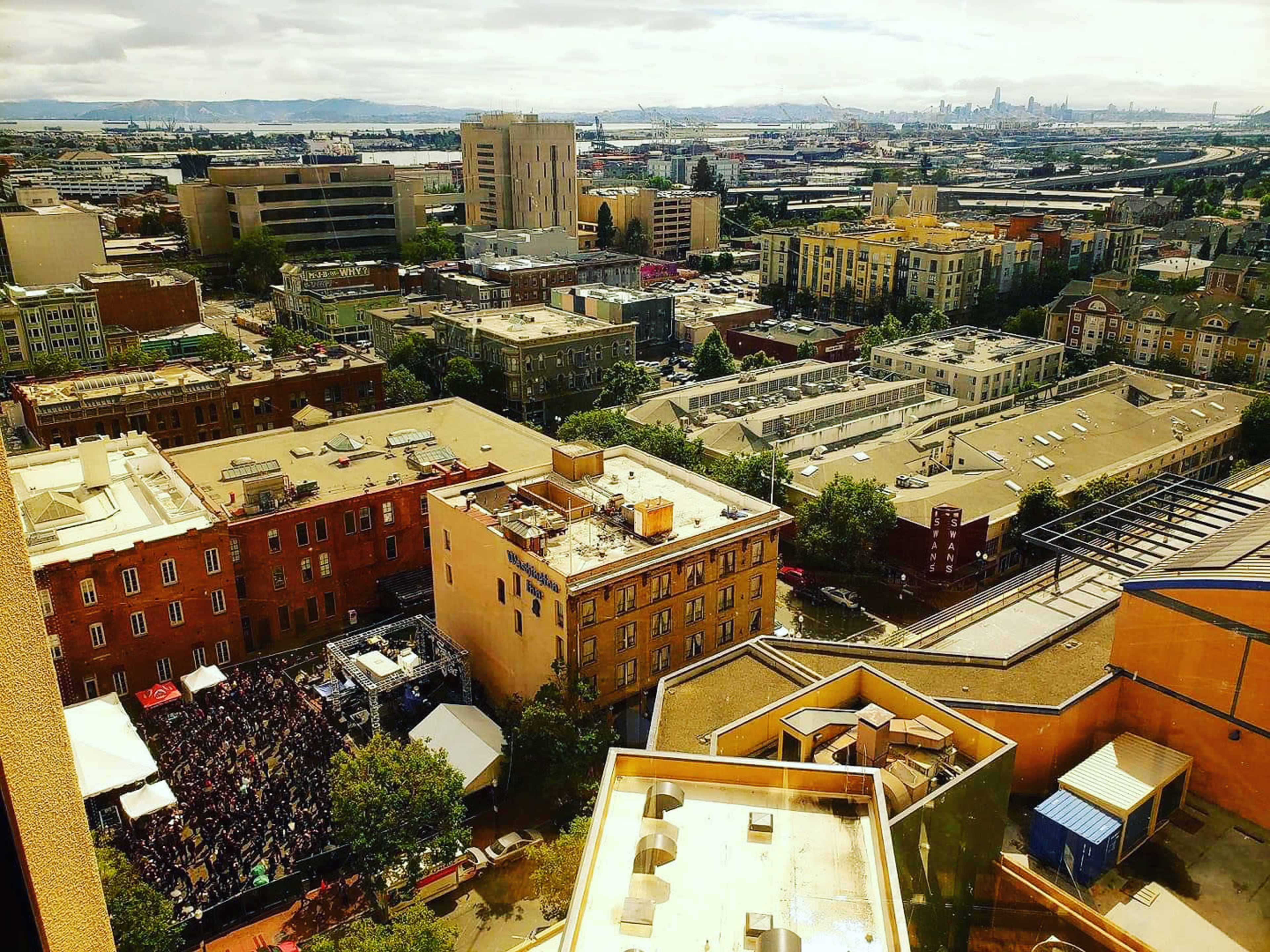 An aerial view of an urban area with several buildings and a large crowd gathered in a square.