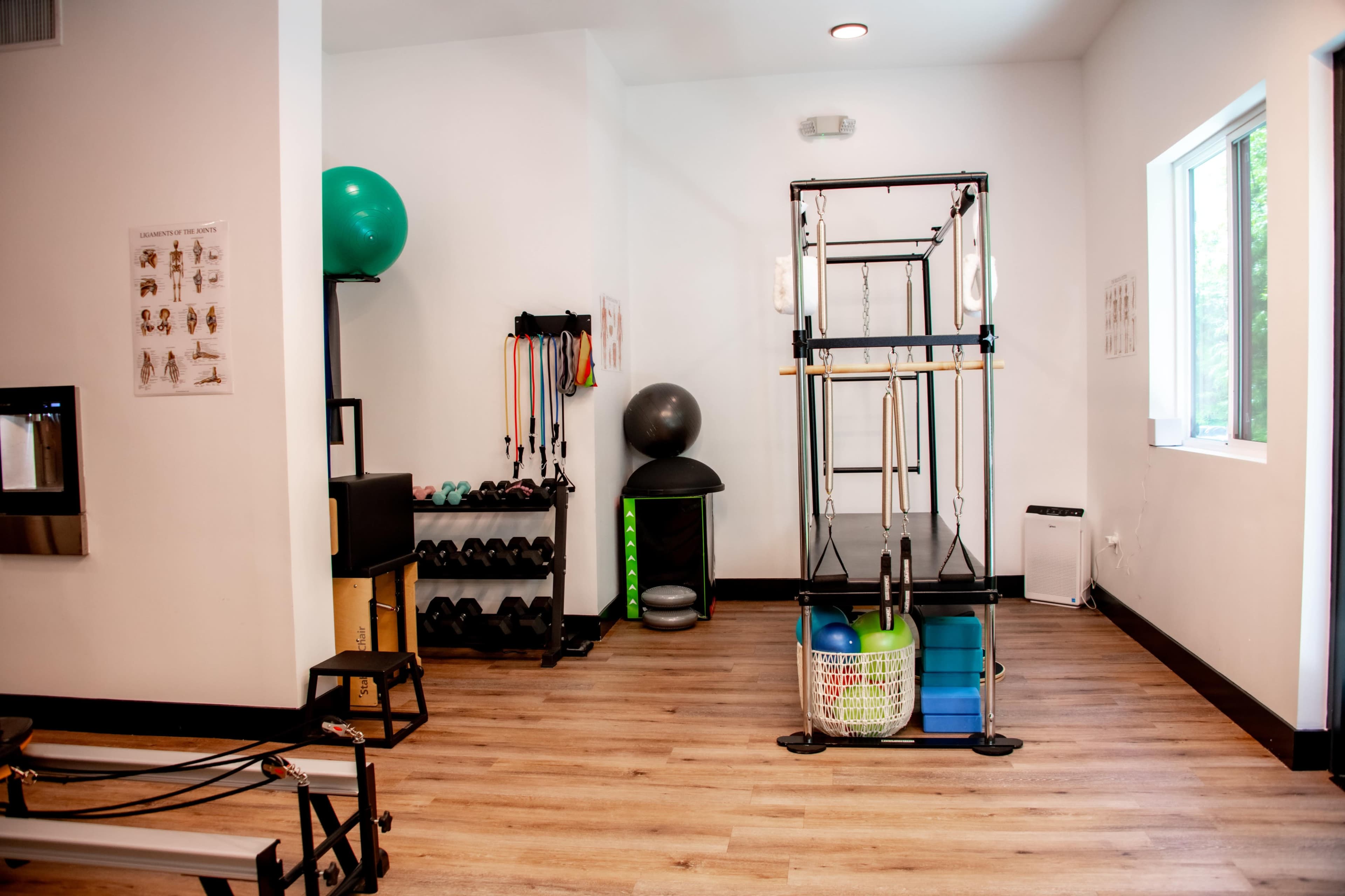 A fitness room equipped with workout machines, weights, exercise balls, and resistance bands.