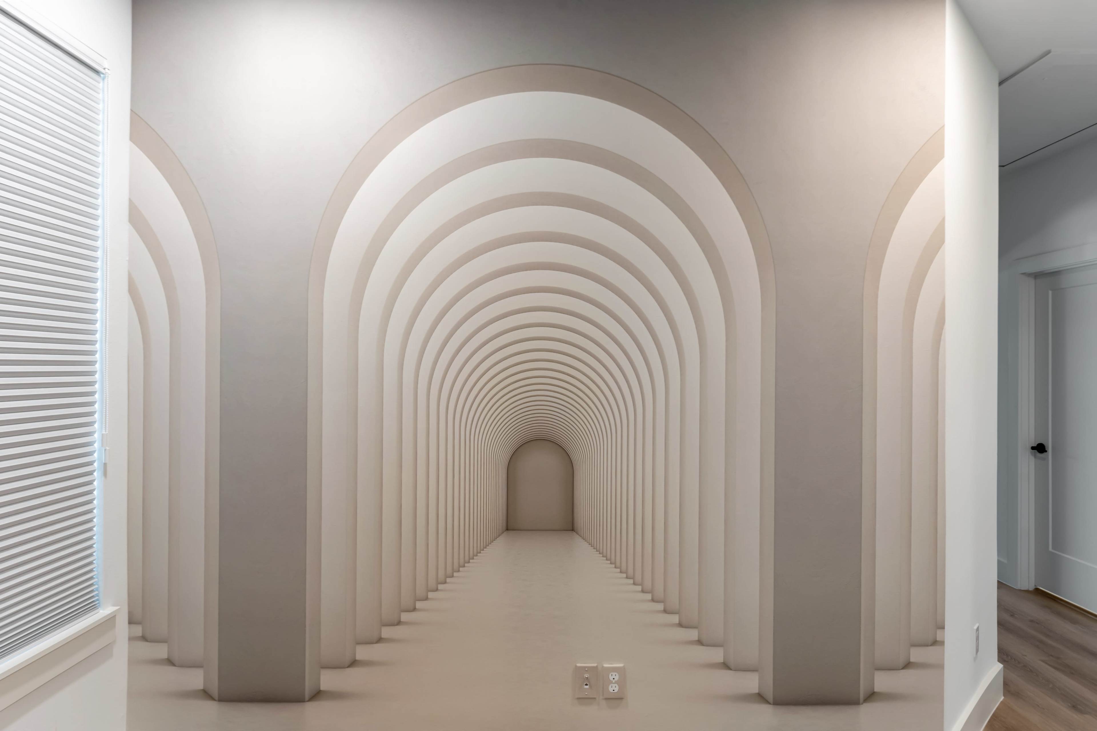 The image features a wall mural depicting a series of arched hallways extending into the distance.