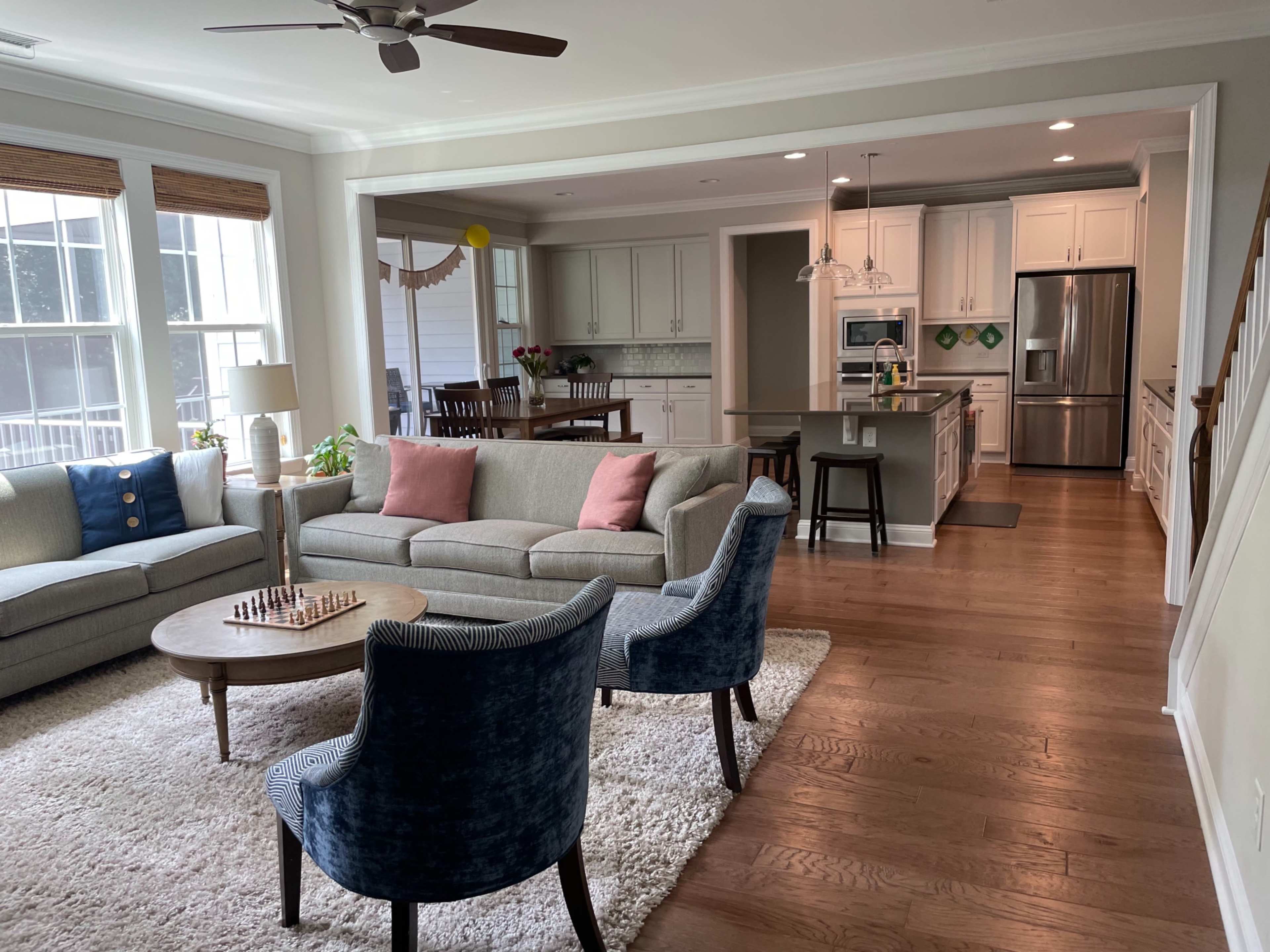 A modern, open-concept living room and kitchen area with a gray sectional sofa, a round table, and a kitchen island.