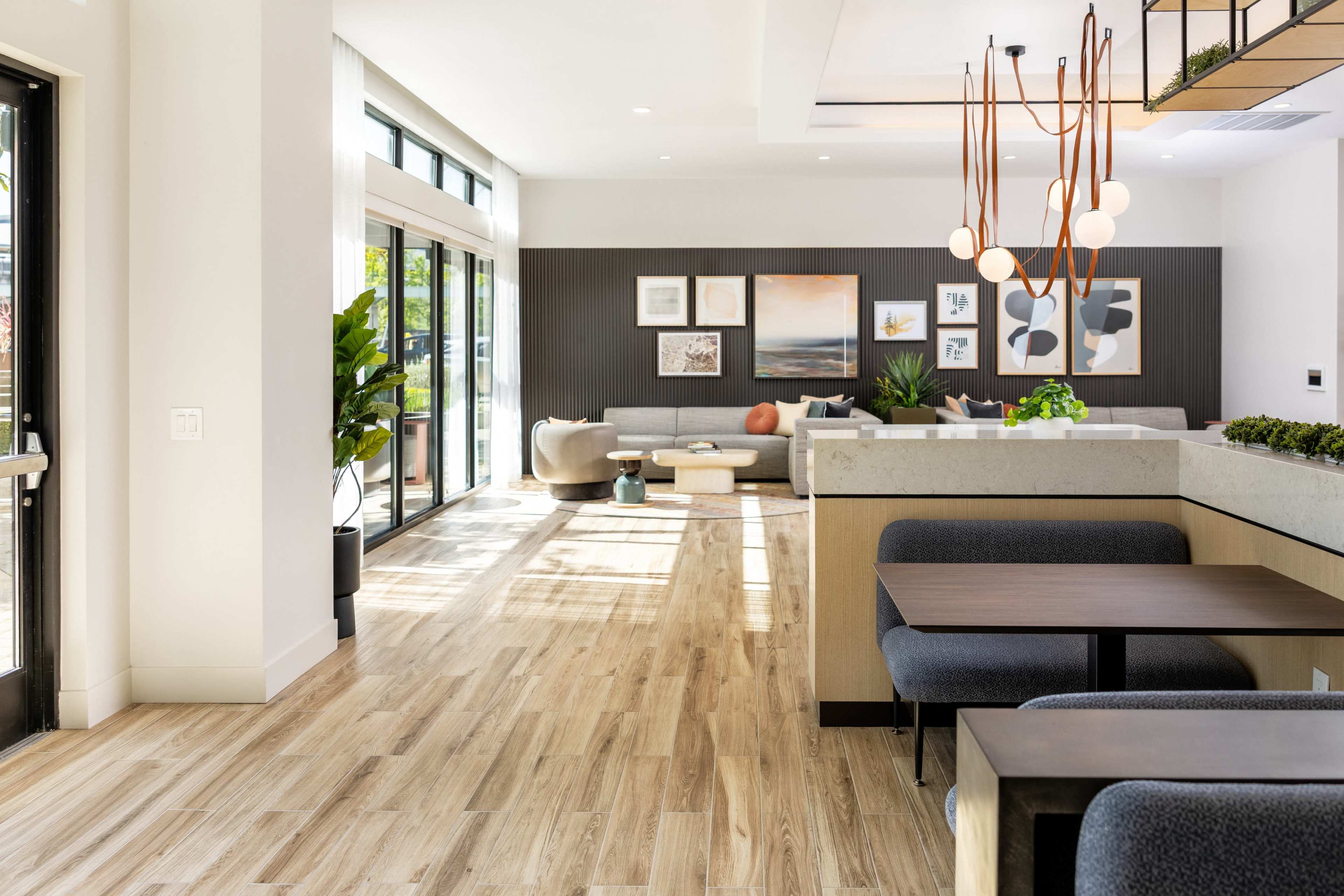 The image shows a modern, bright interior with a seating area, large windows, and decorative artwork on the walls.
