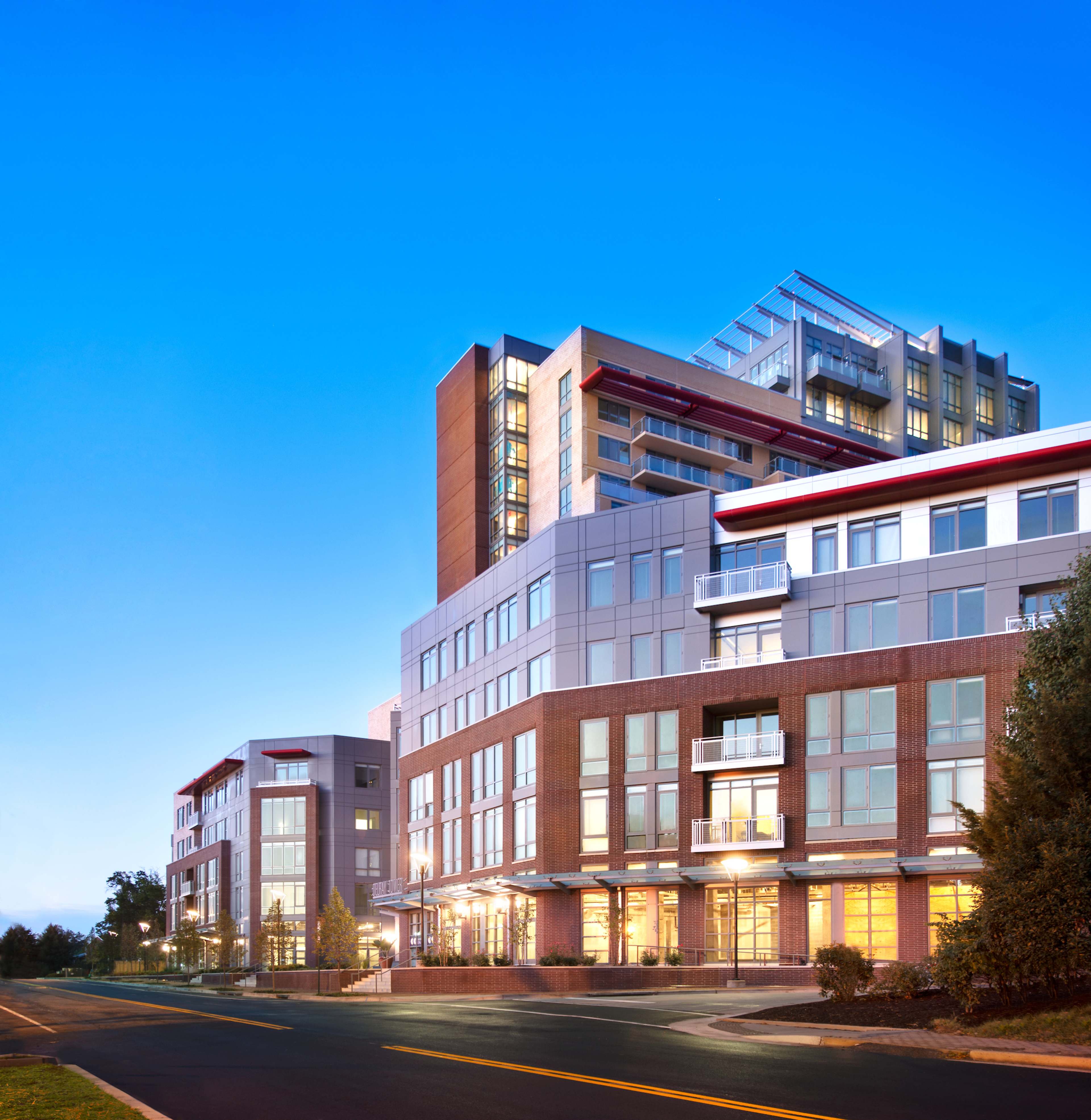 A modern multi-story building complex with a glass and brick facade, located at the intersection of a road.