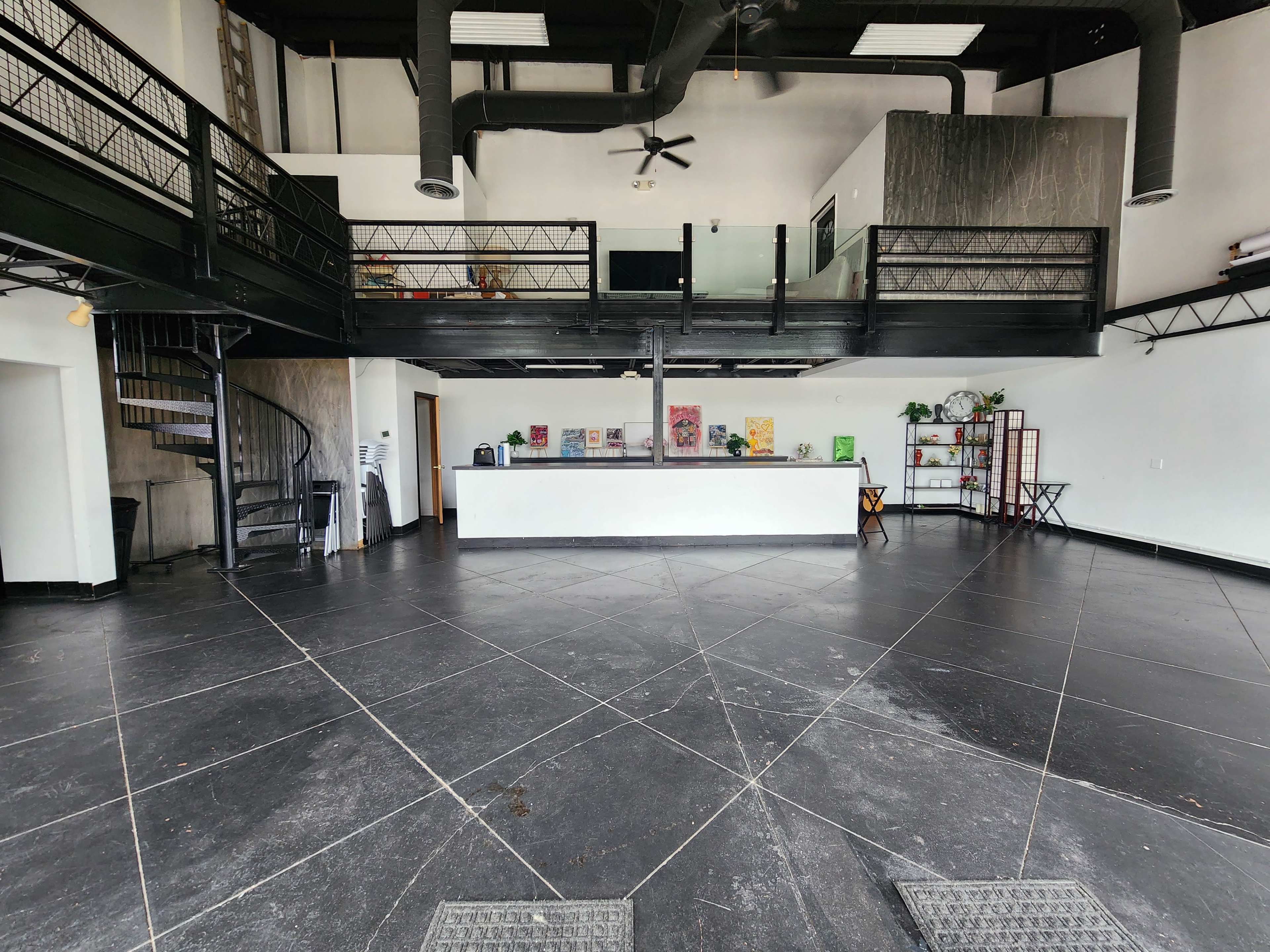 The interior of a spacious commercial building features a two-level layout with a spiral staircase and a reception area at the front.