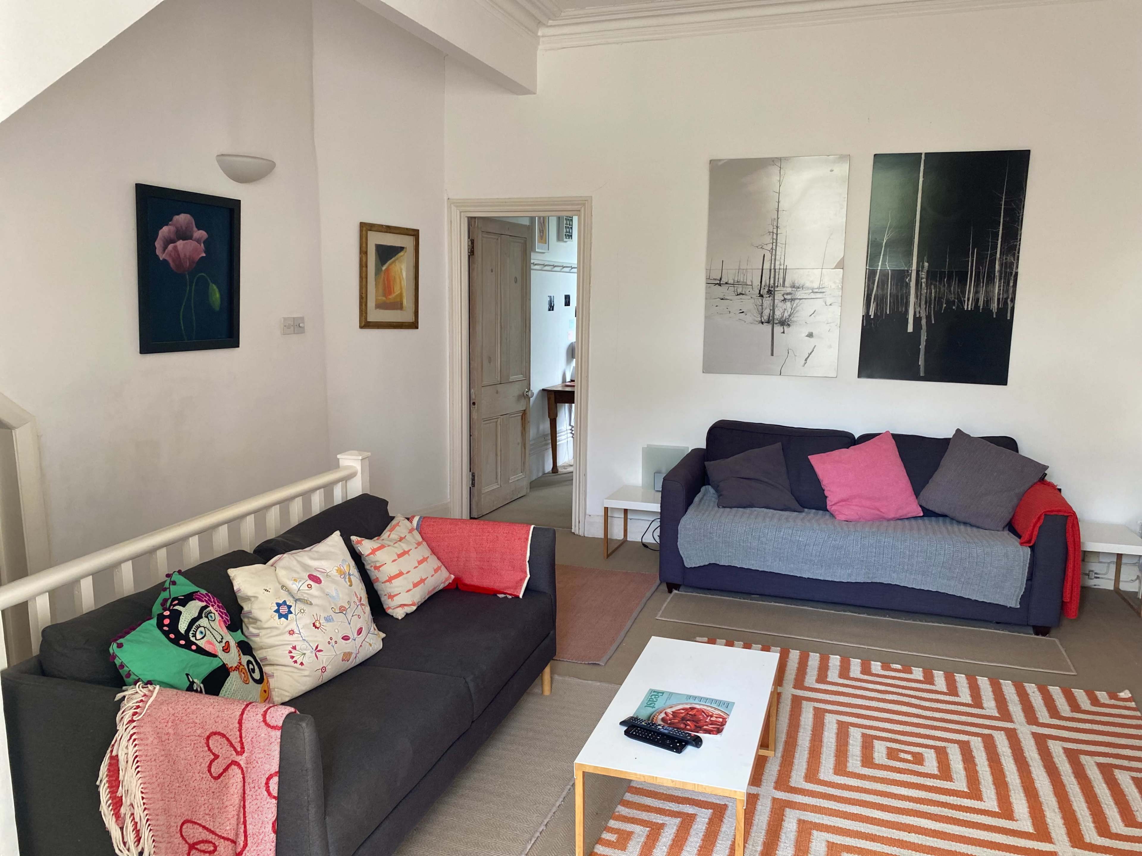 A living room with two sofas, decorative cushions, wall art, and a coffee table on a patterned rug.