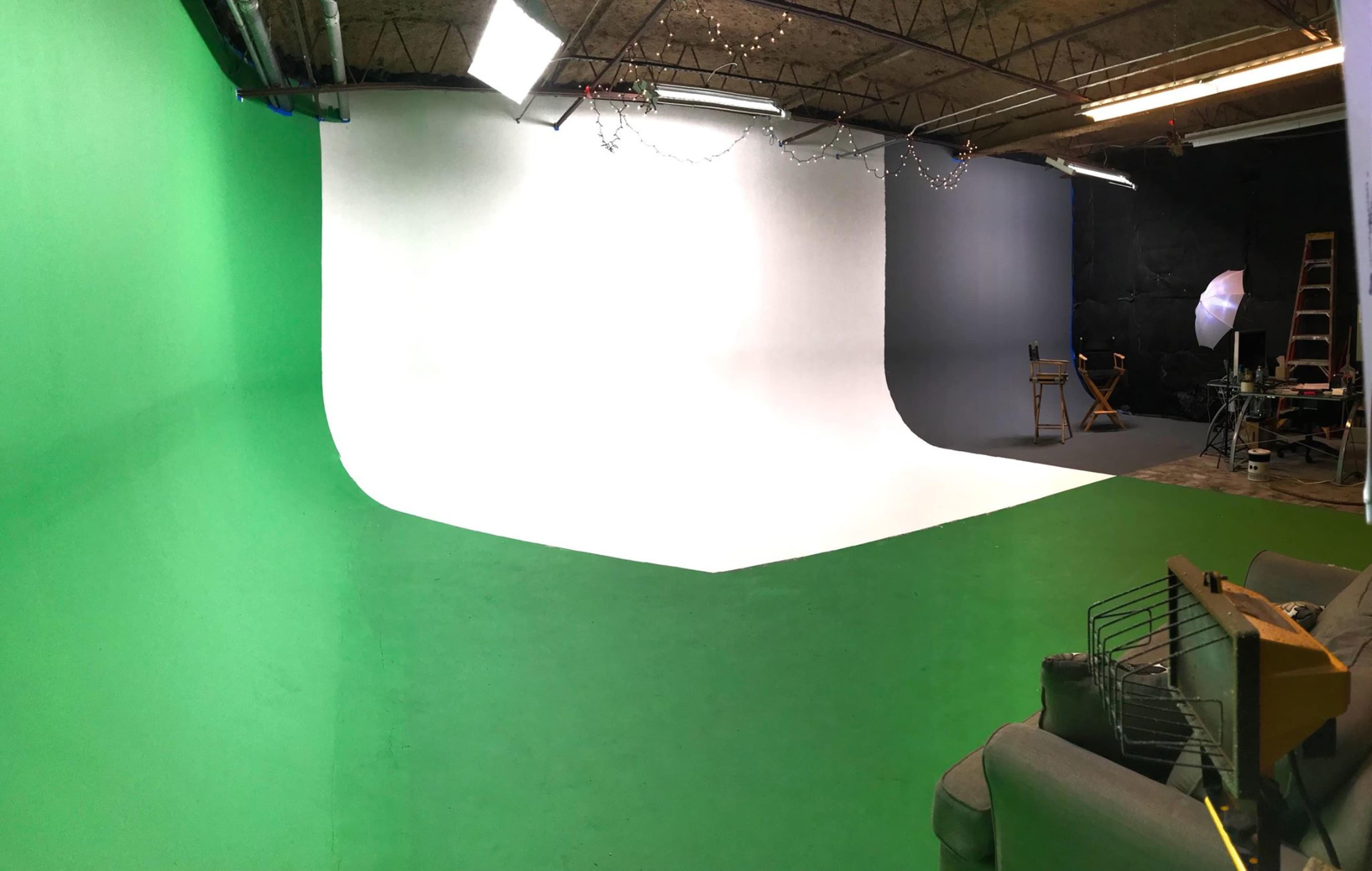 A photography studio with a green, white, and gray backdrop, along with various studio equipment and furniture.