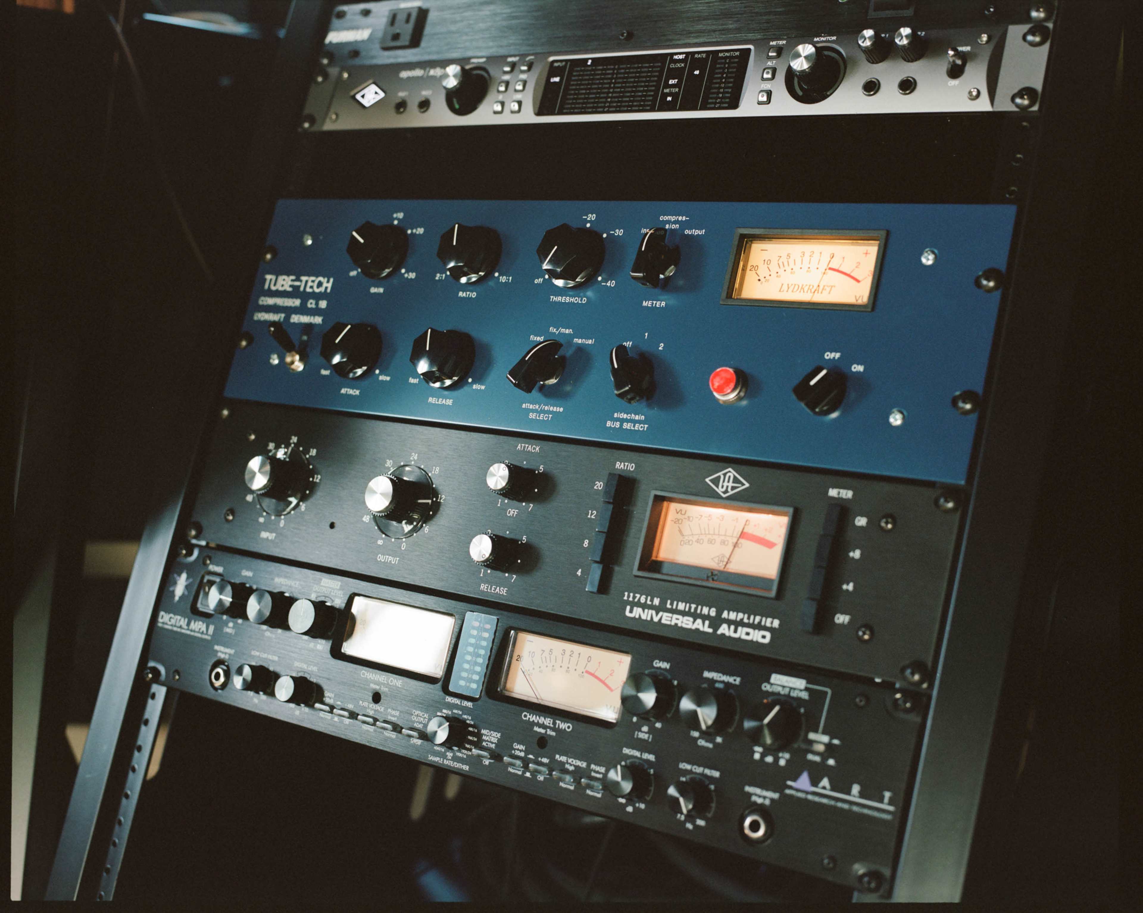 The image shows a rack-mounted audio equipment setup featuring various knobs, meters, and controls for sound processing and amplification.