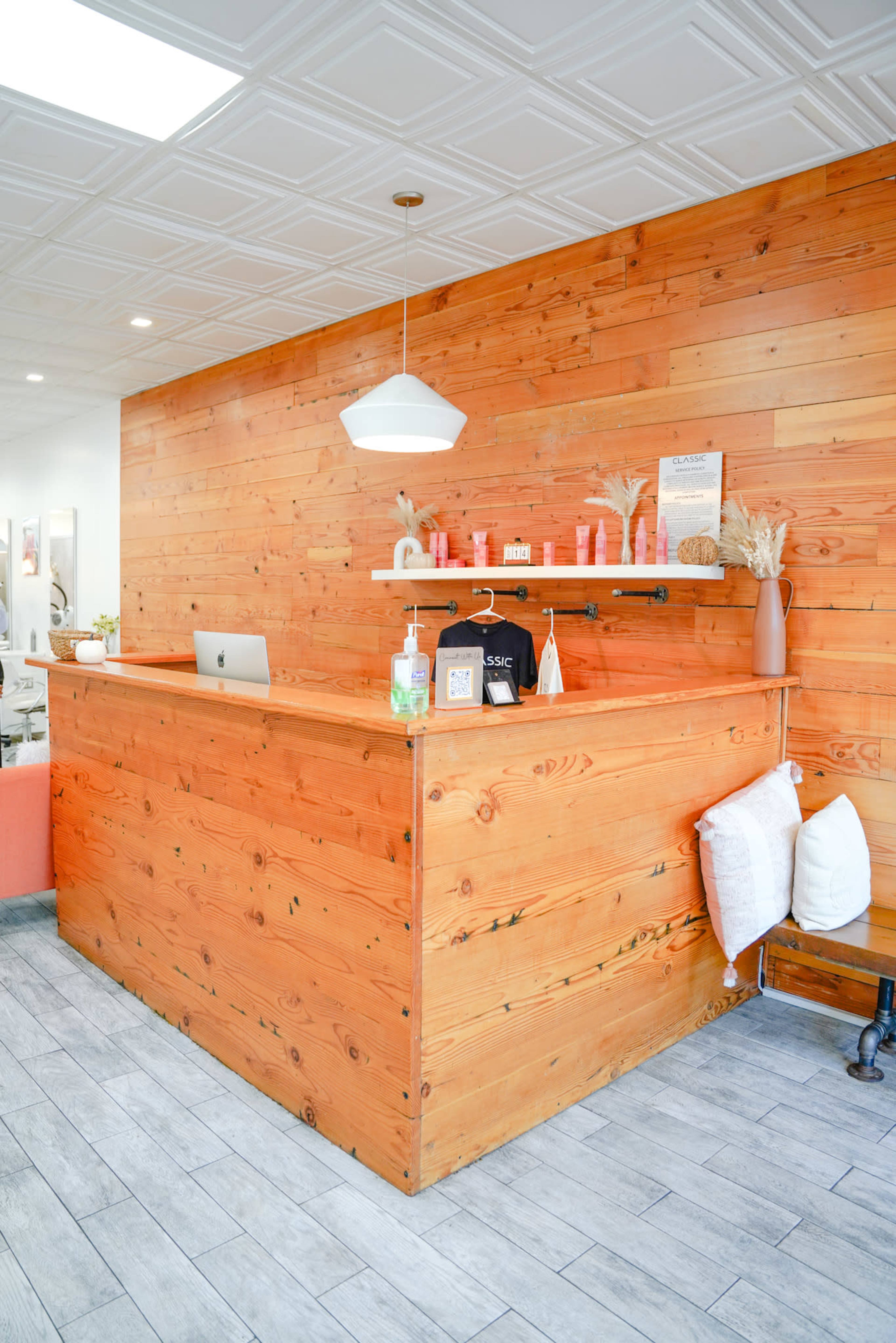 A wooden reception desk in a modern interior space, featuring a minimalist design with decor items and a computer setup.