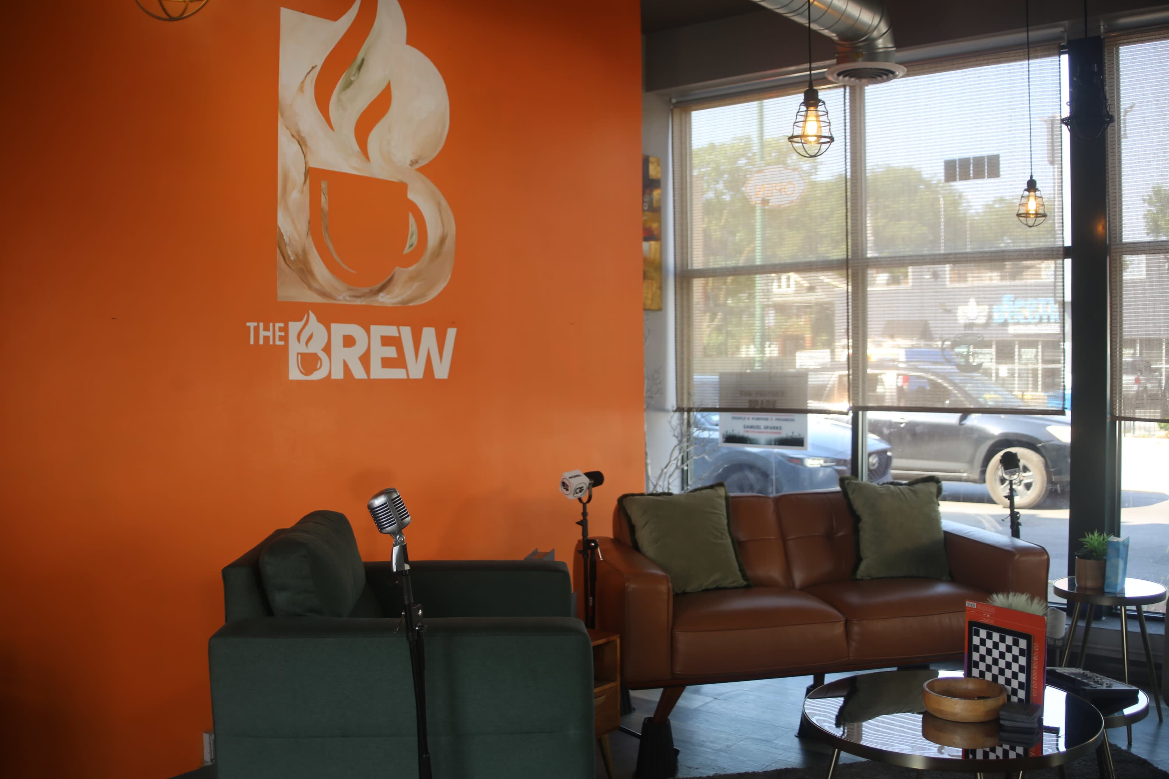 The image shows a cozy café interior with orange walls, two seating areas, and a large window overlooking a street.