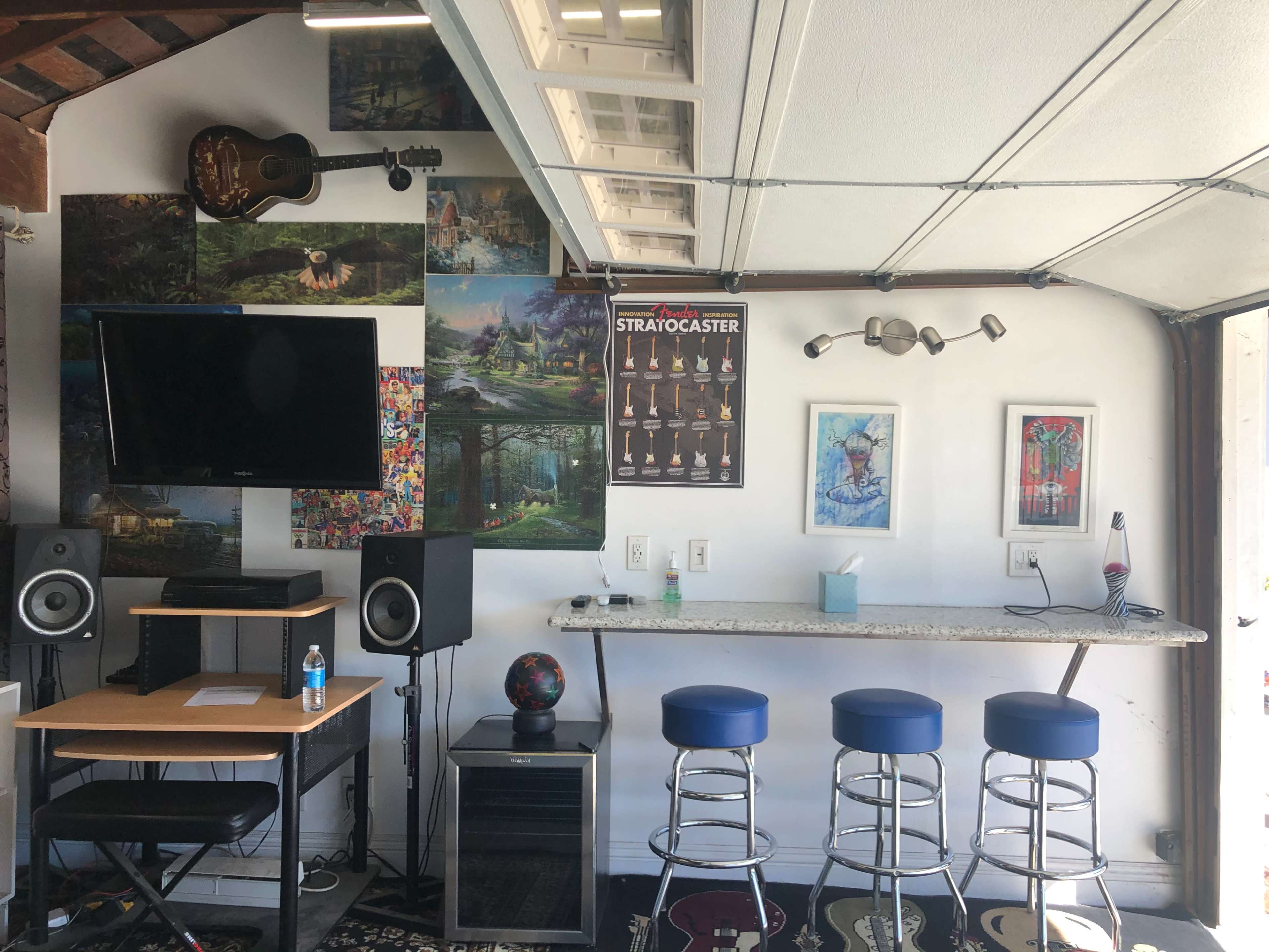 A garage space with a bar counter, a television, speakers, and music-themed decor on the walls.