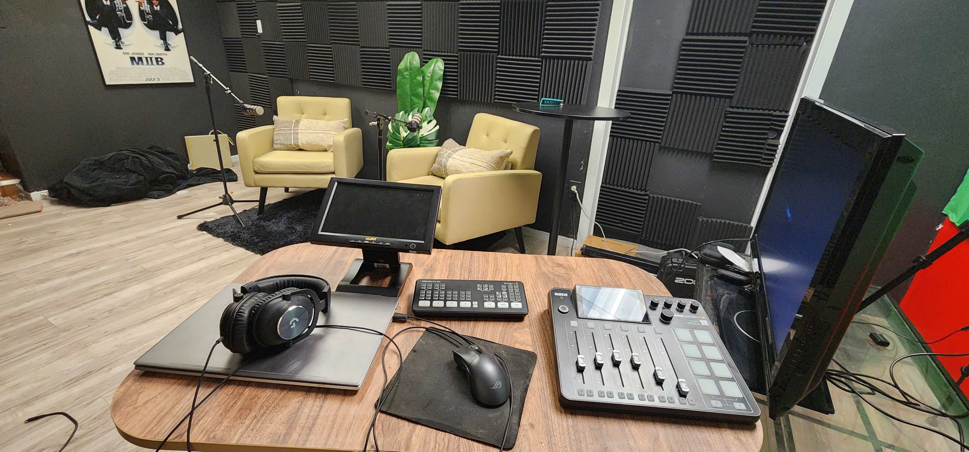 The image shows a recording studio setup with two yellow chairs, a microphone, and various audio equipment on a table.