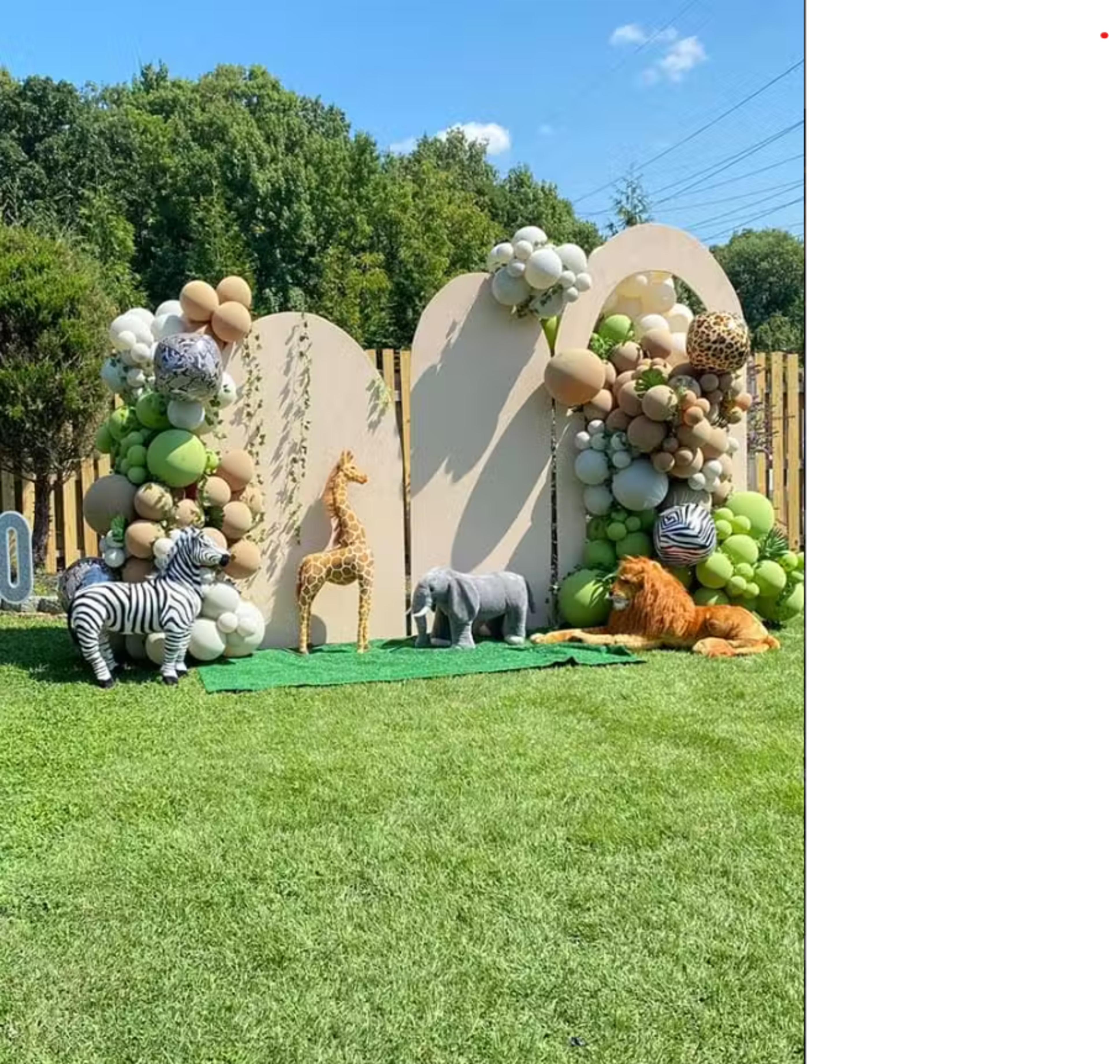 The scene features a decorative arrangement with balloon archways and stuffed animal figures, set in a grassy area with trees in the background.