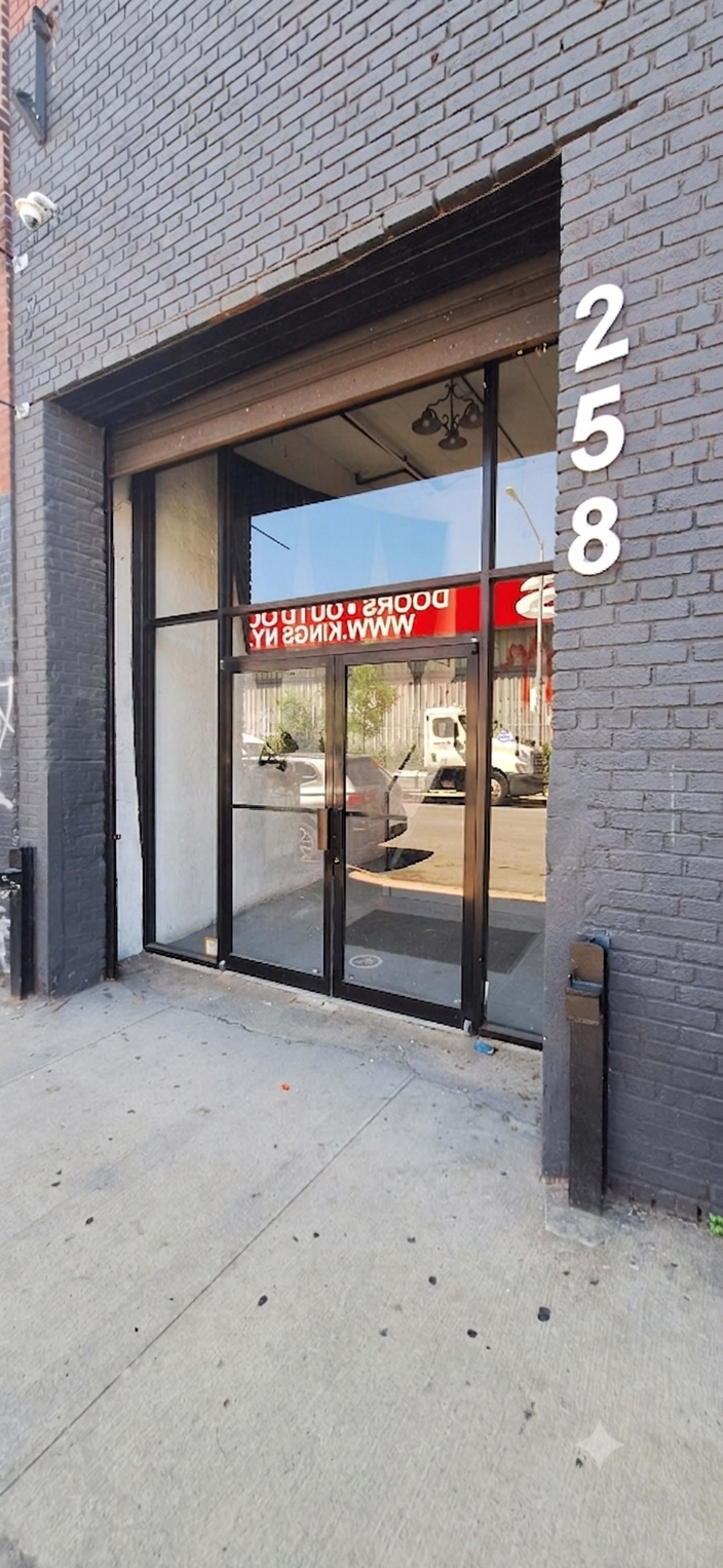 The image shows a storefront with large glass doors and the number "258" displayed prominently on the wall beside it.