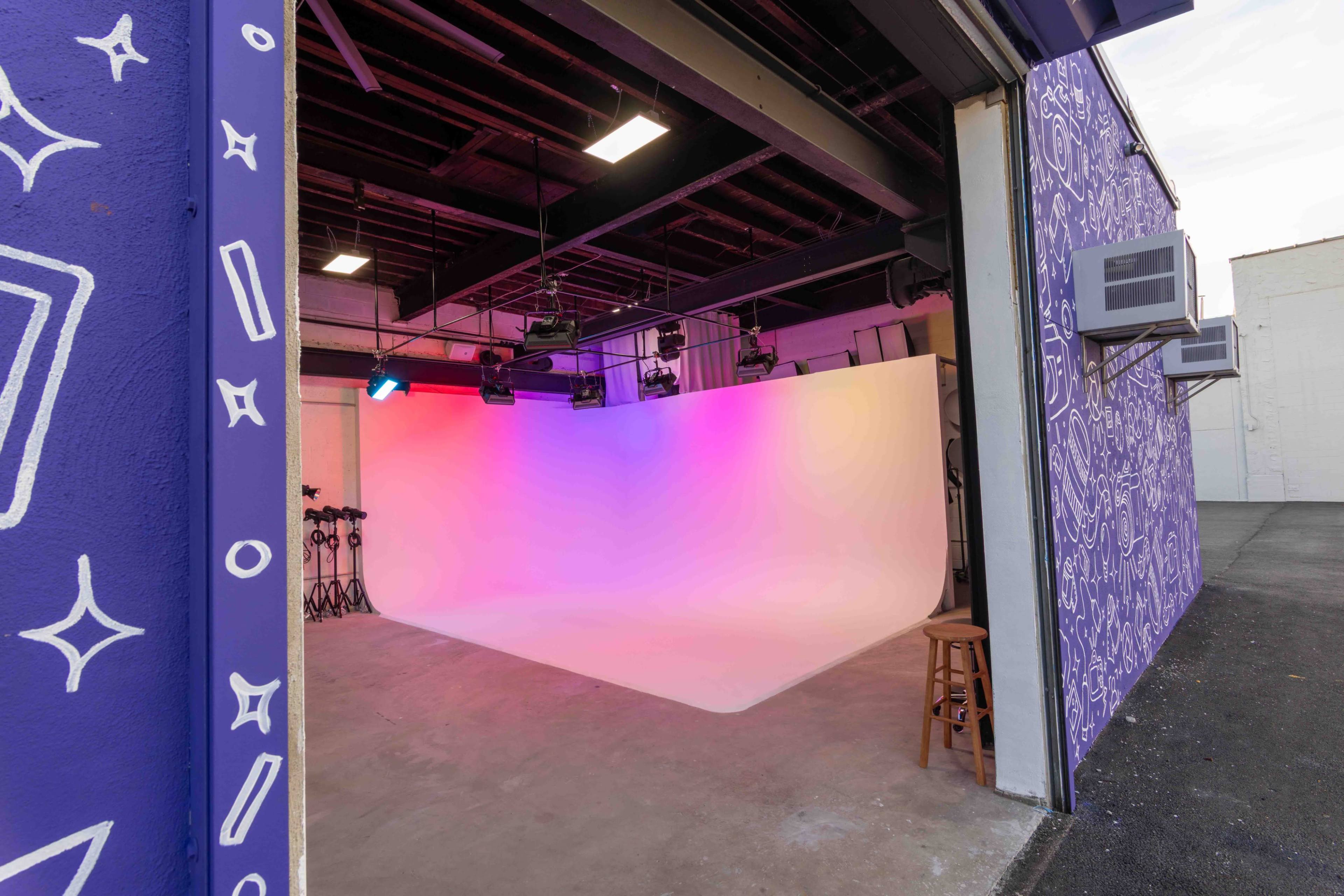 The image shows a photography studio with a gradient backdrop and multiple lights, accessible through an open garage door.