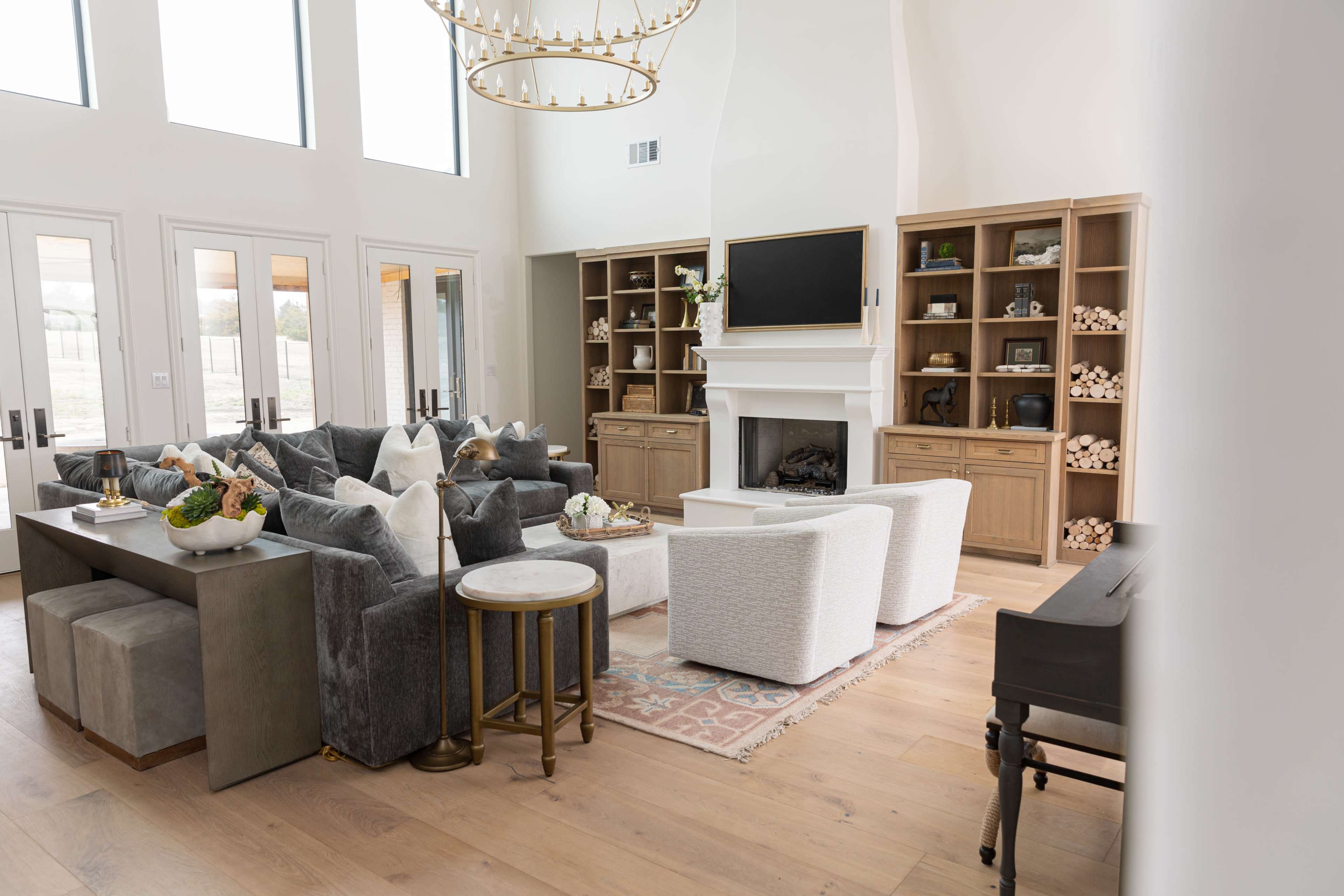 The living room features a mix of comfortable seating, a fireplace, built-in shelves, and large windows allowing natural light inside.