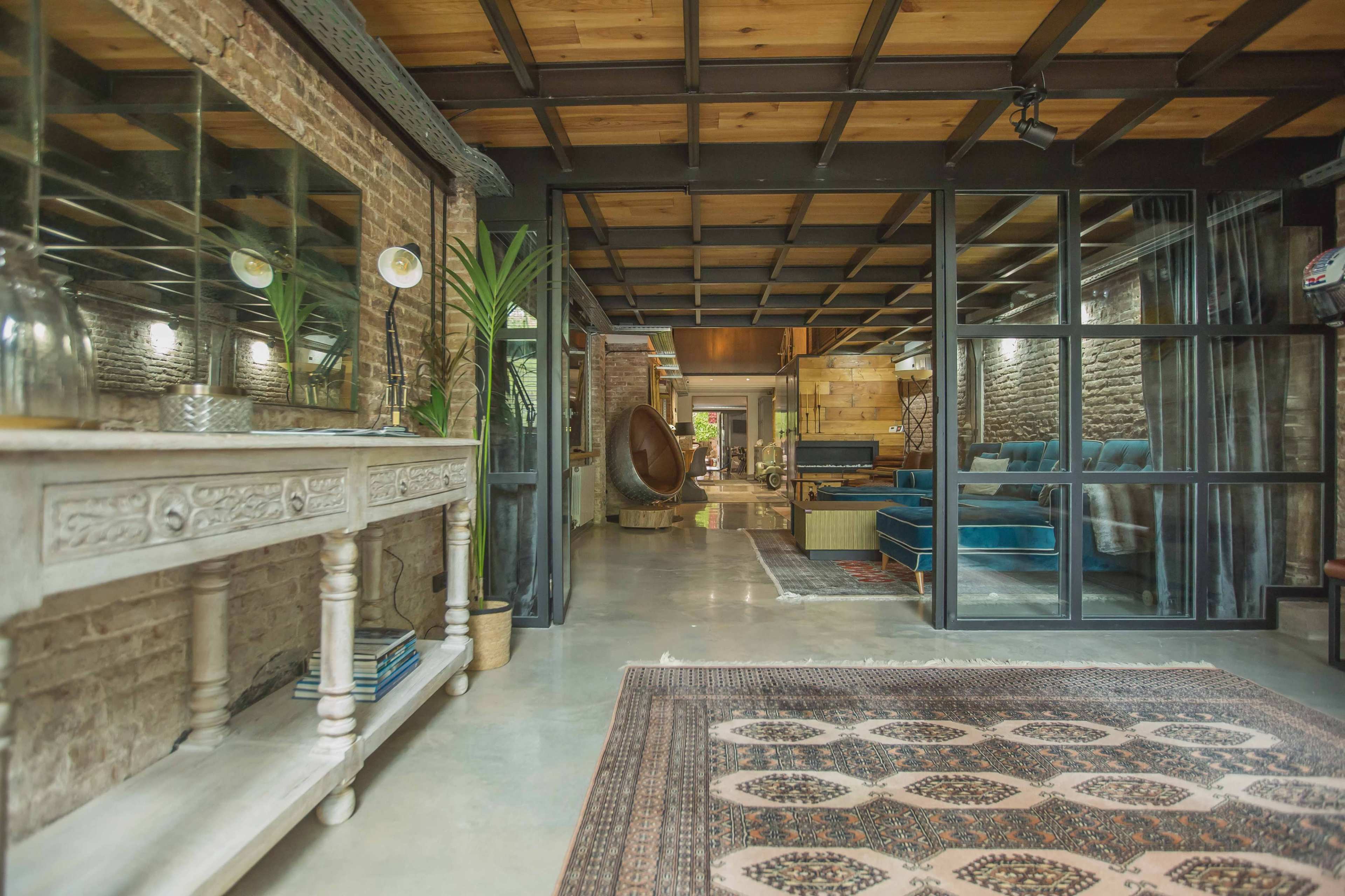 An open interior space featuring a decorative console table, plants, and a view into a living area with wooden beams and modern furniture.