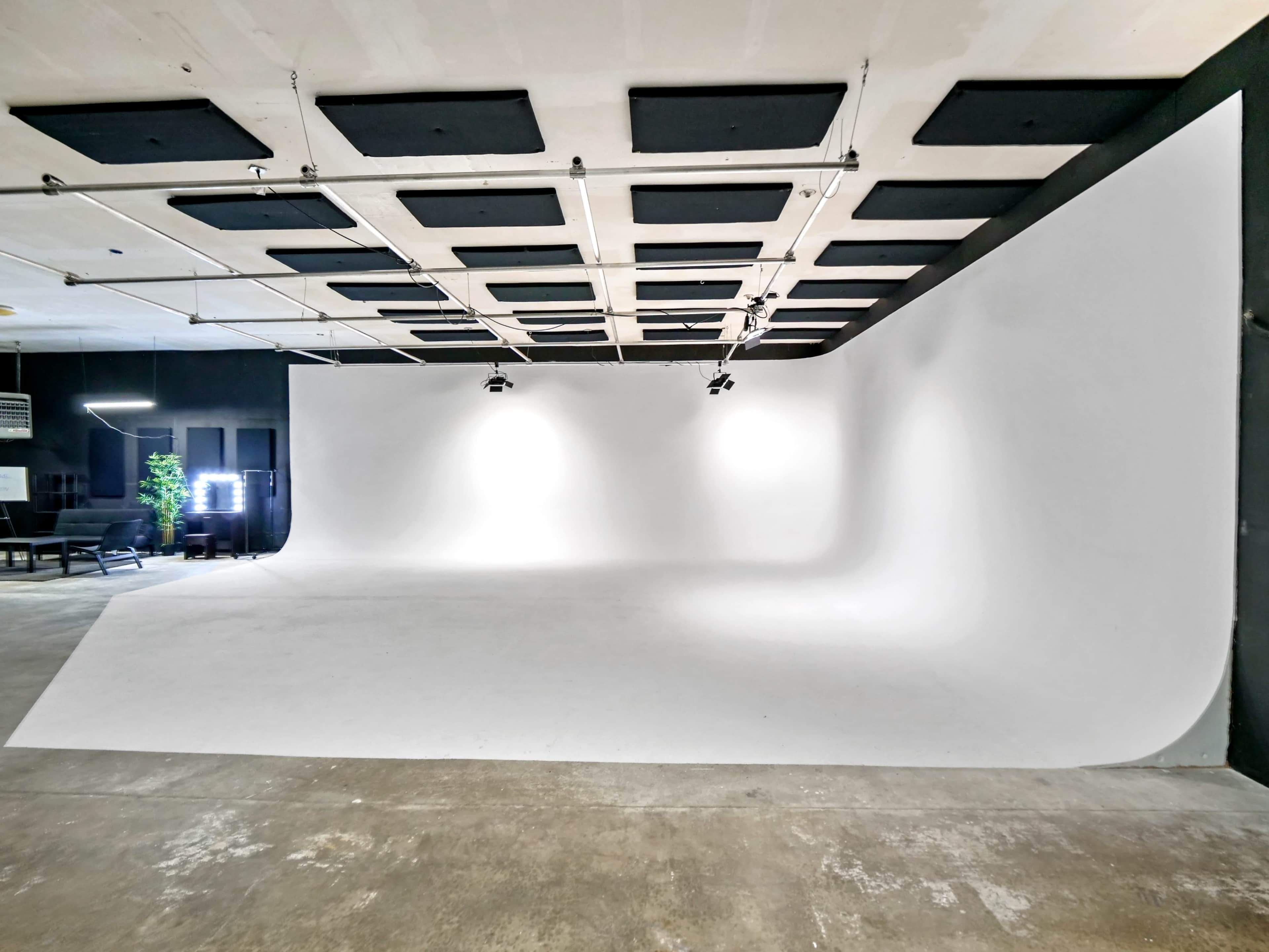 A spacious photography studio with a curved white backdrop and a concrete floor.