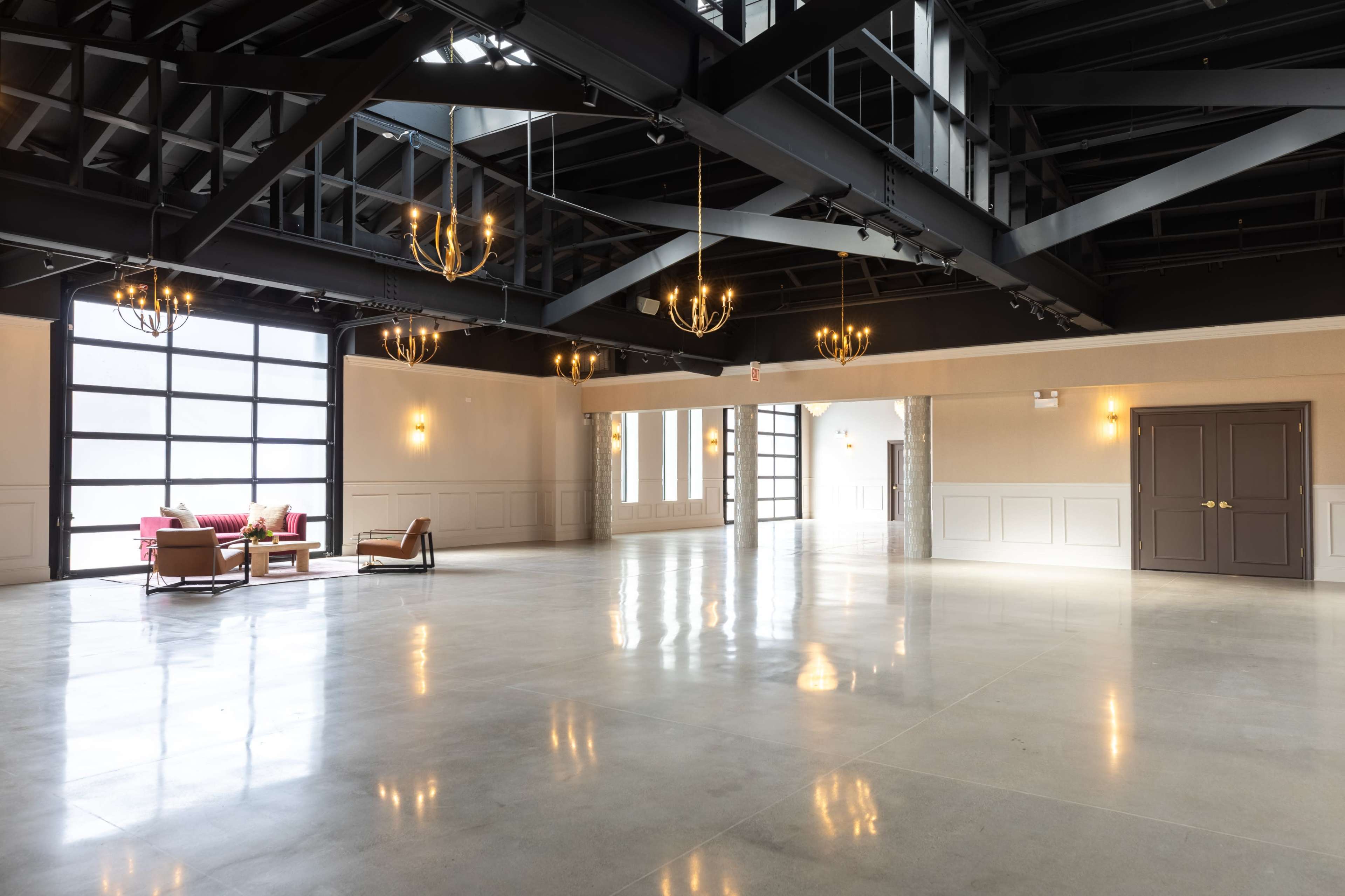 The image shows a spacious, modern event hall with large windows, high ceilings, and minimalist décor.