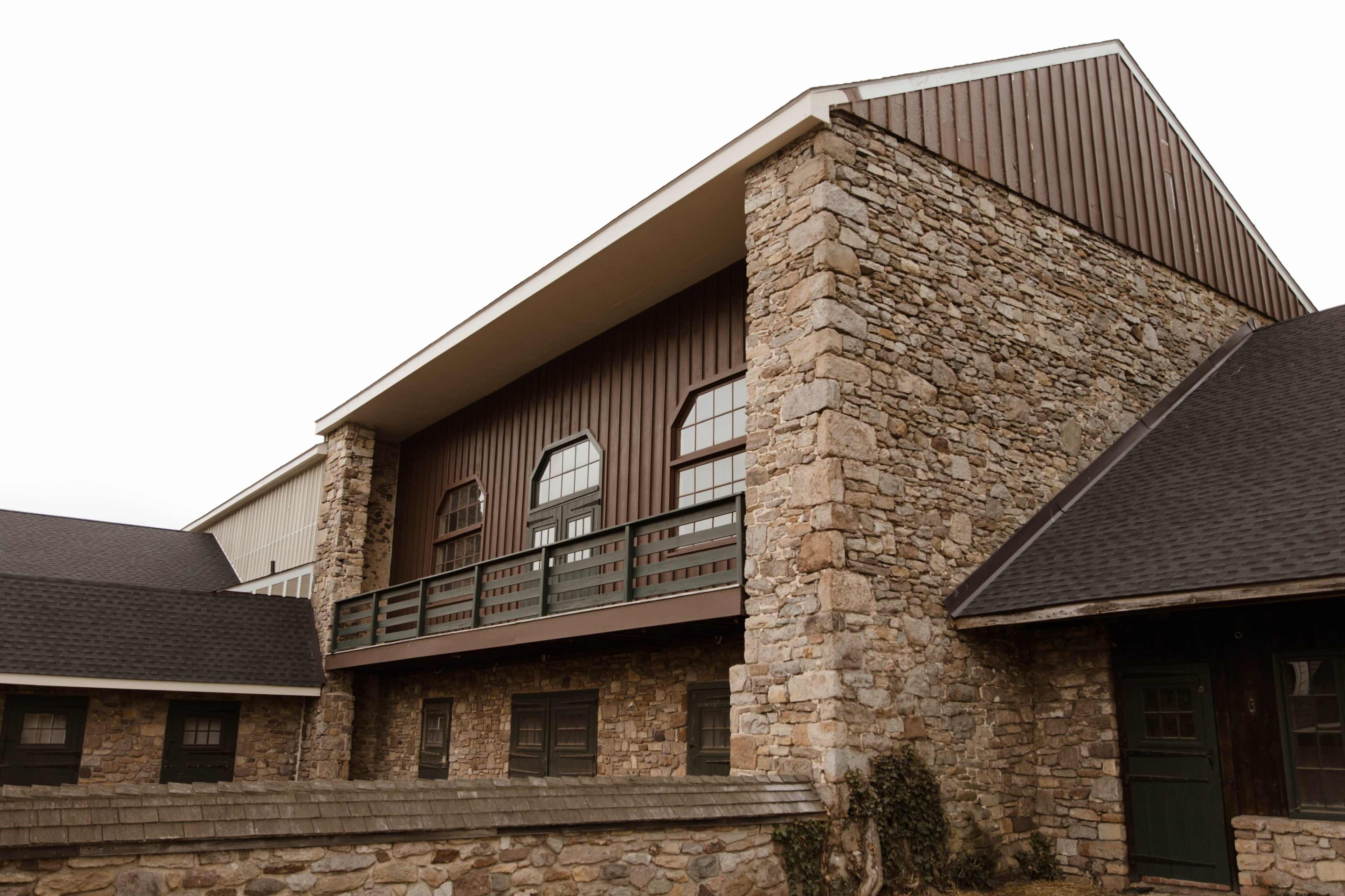 A large building featuring a combination of stone and wood siding with multiple windows and a balcony on the upper level.