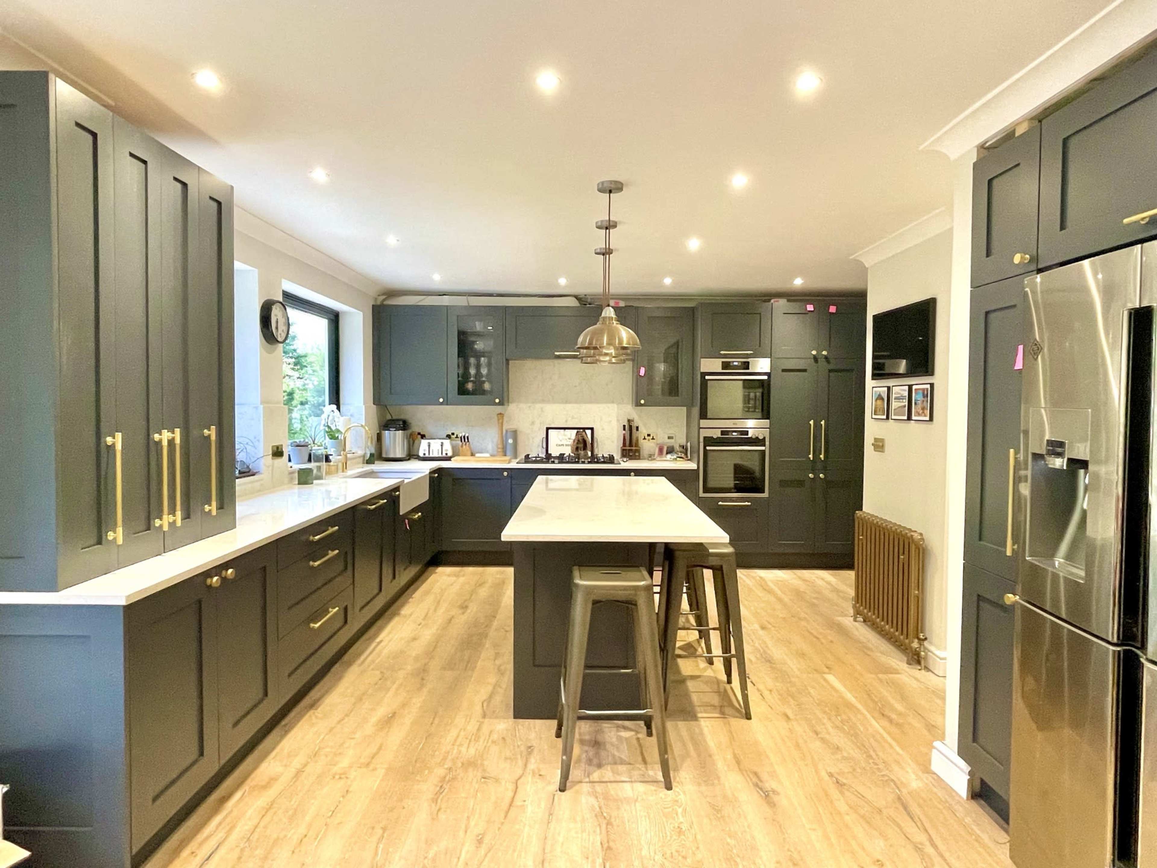 A modern kitchen featuring dark cabinetry, a central island with seating, and stainless steel appliances.