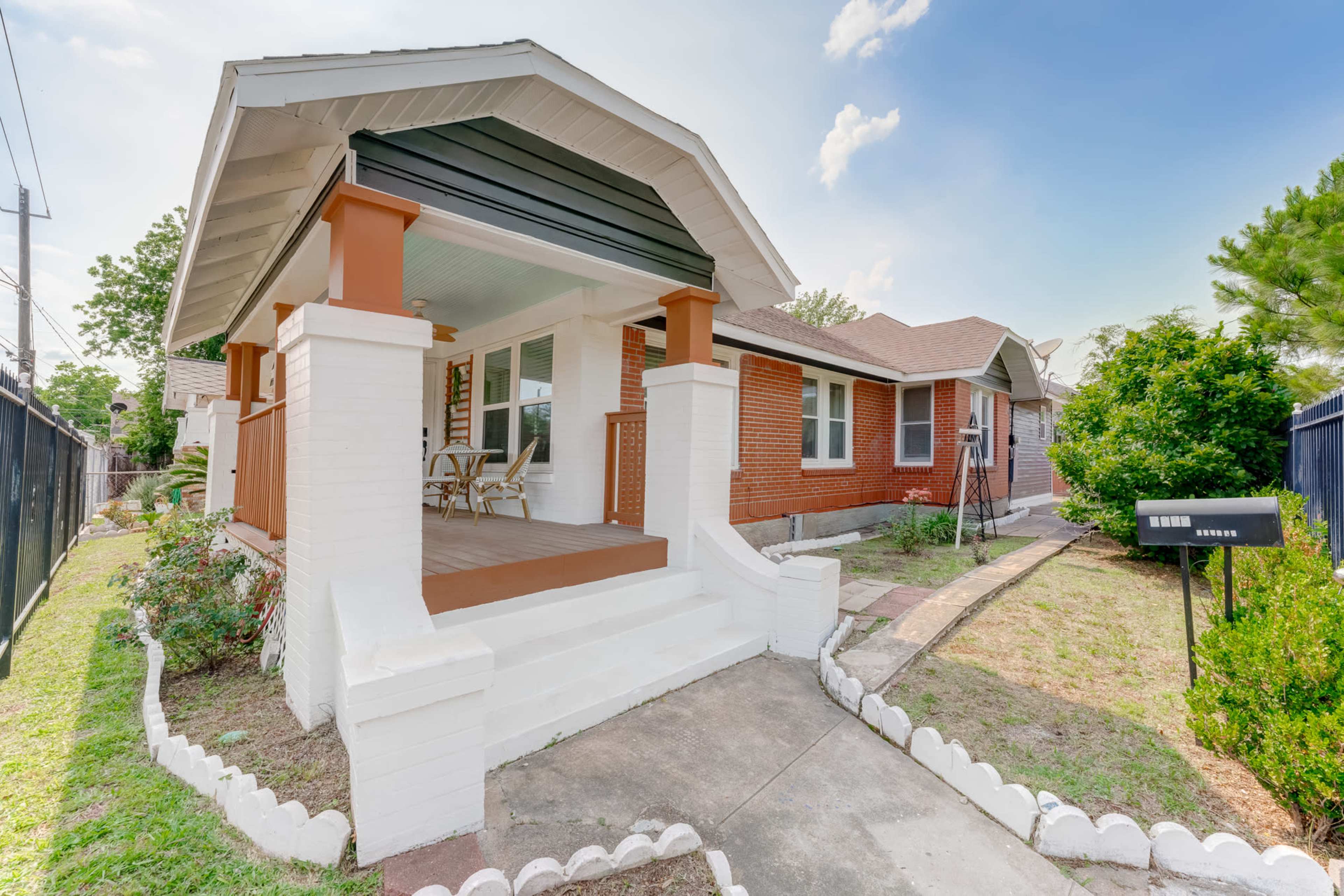 A single-story brick house with a front porch, white columns, and a well-defined walkway leading to a mailbox.