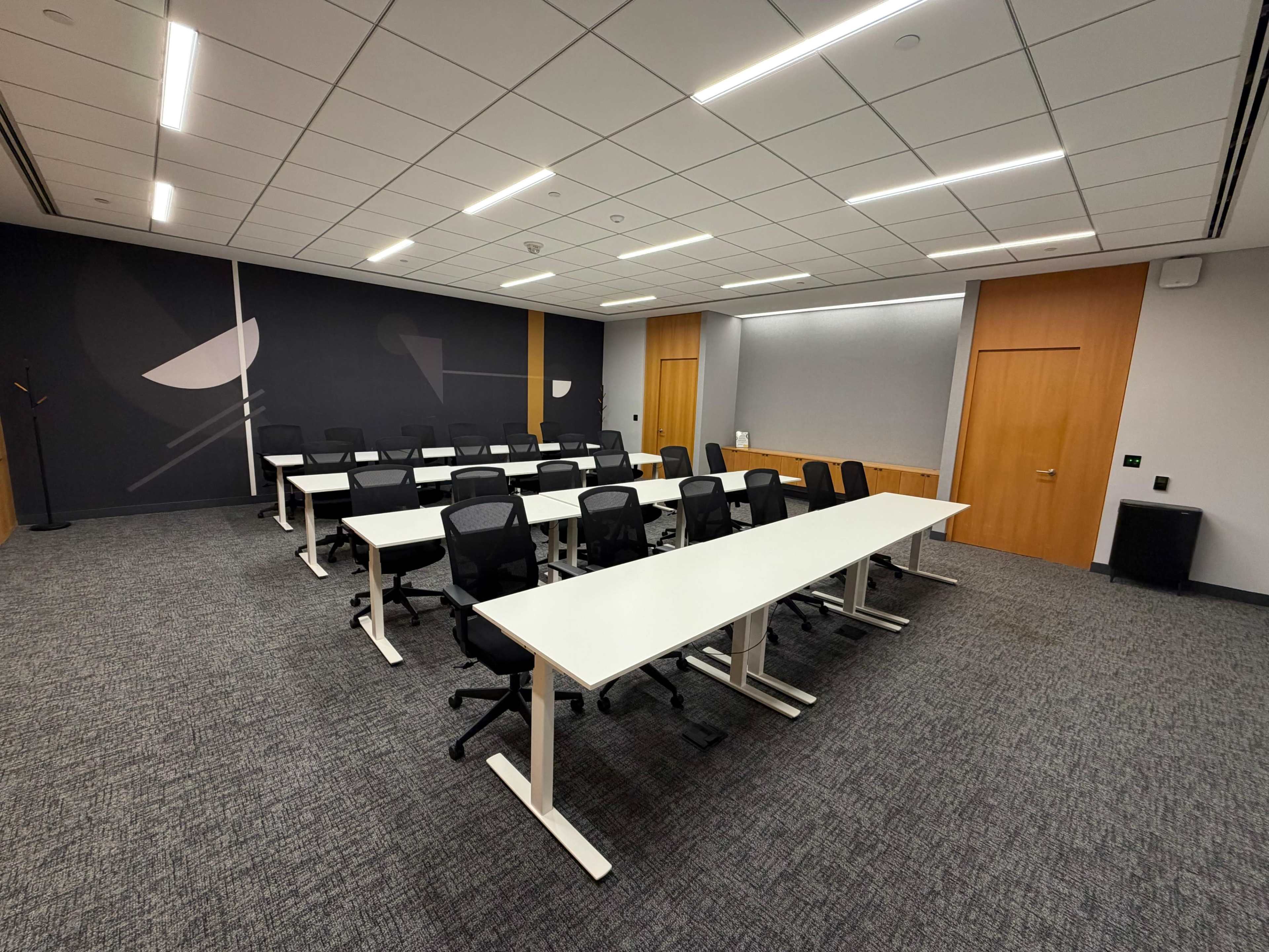 The image shows a modern conference room arranged with multiple white tables and black ergonomic chairs.