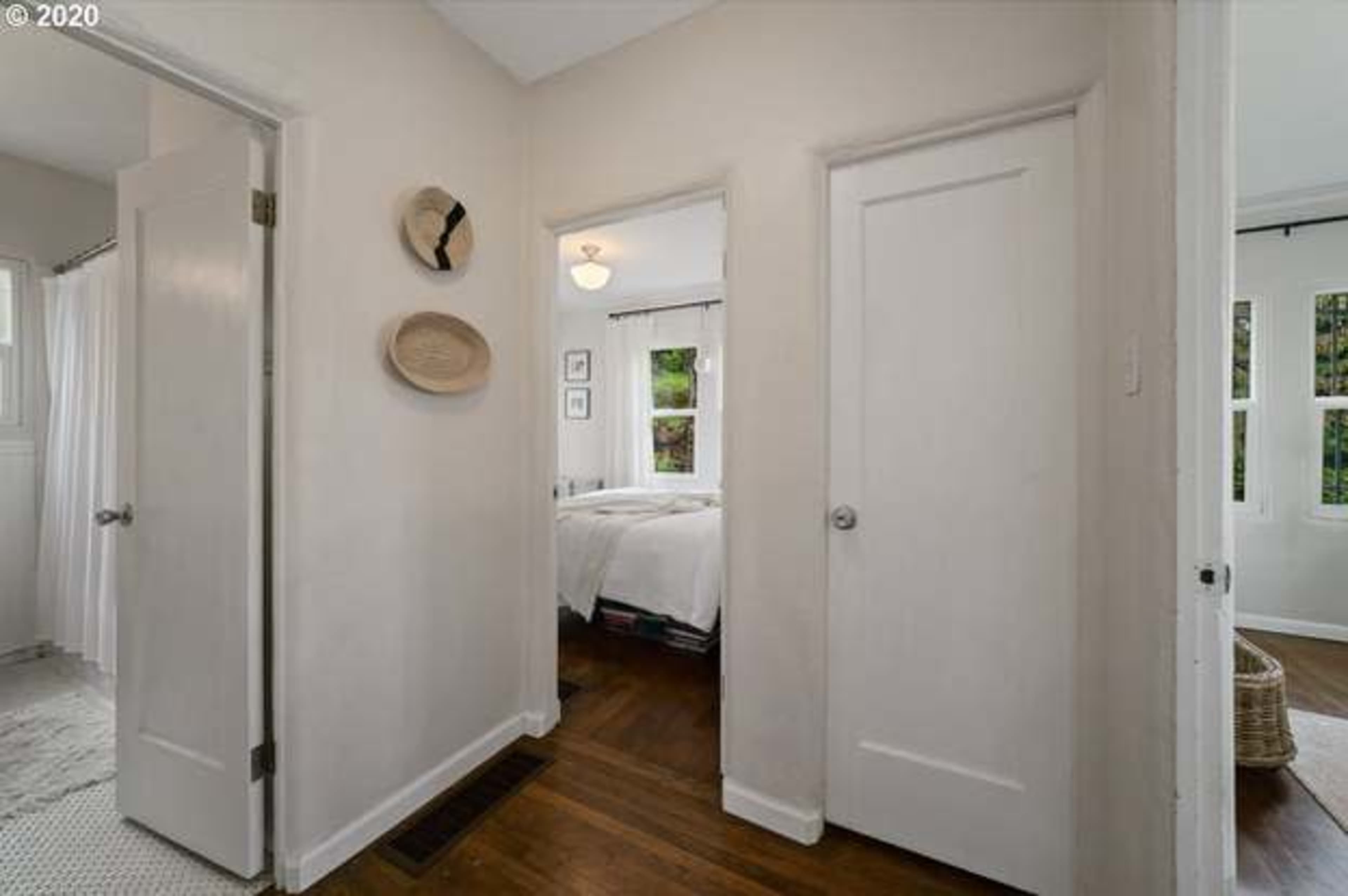 A narrow hallway features two doors leading to adjacent rooms, with wall decor and a light fixture overhead.