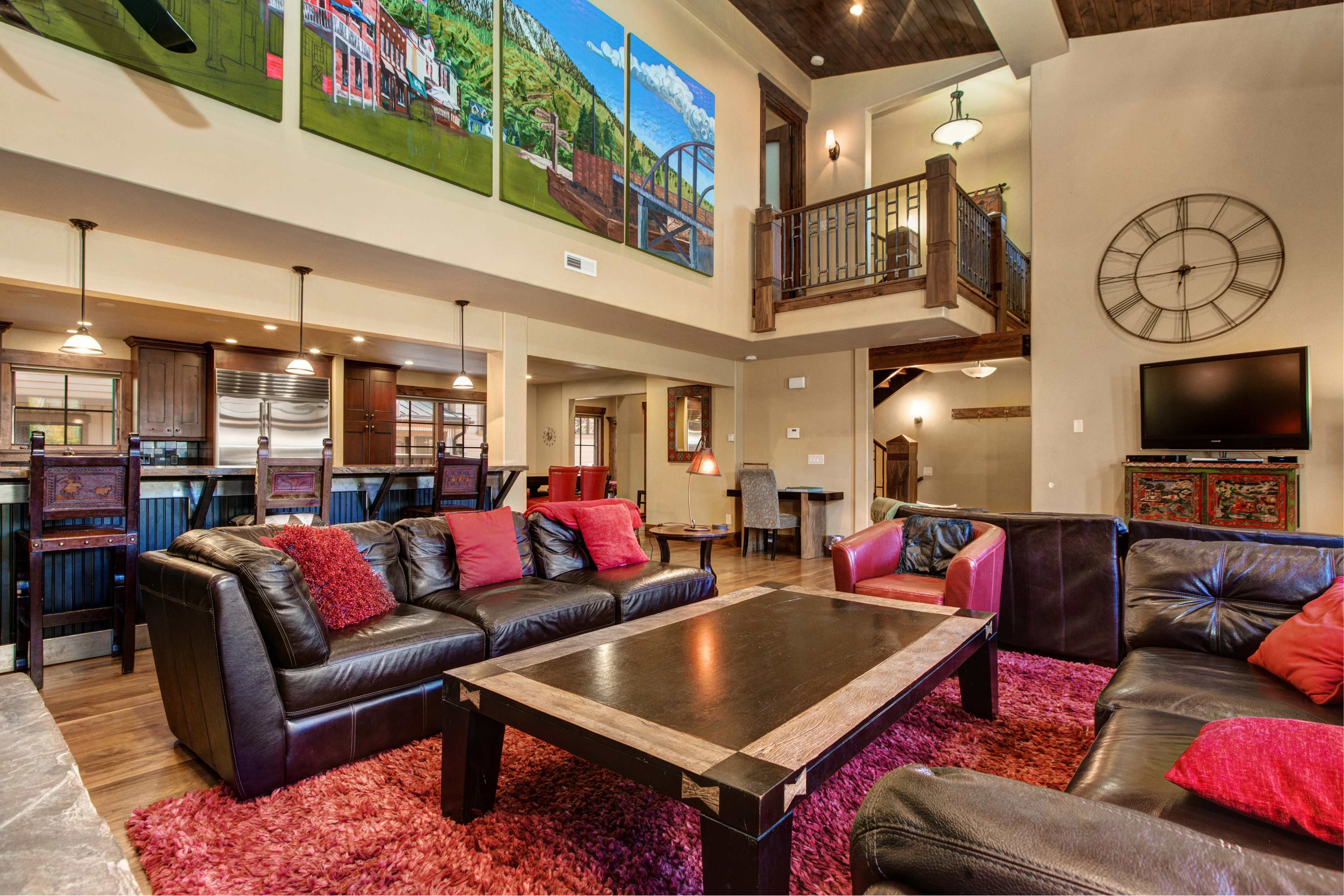 A spacious living room with leather sofas, a large coffee table, and vibrant artwork on the walls.