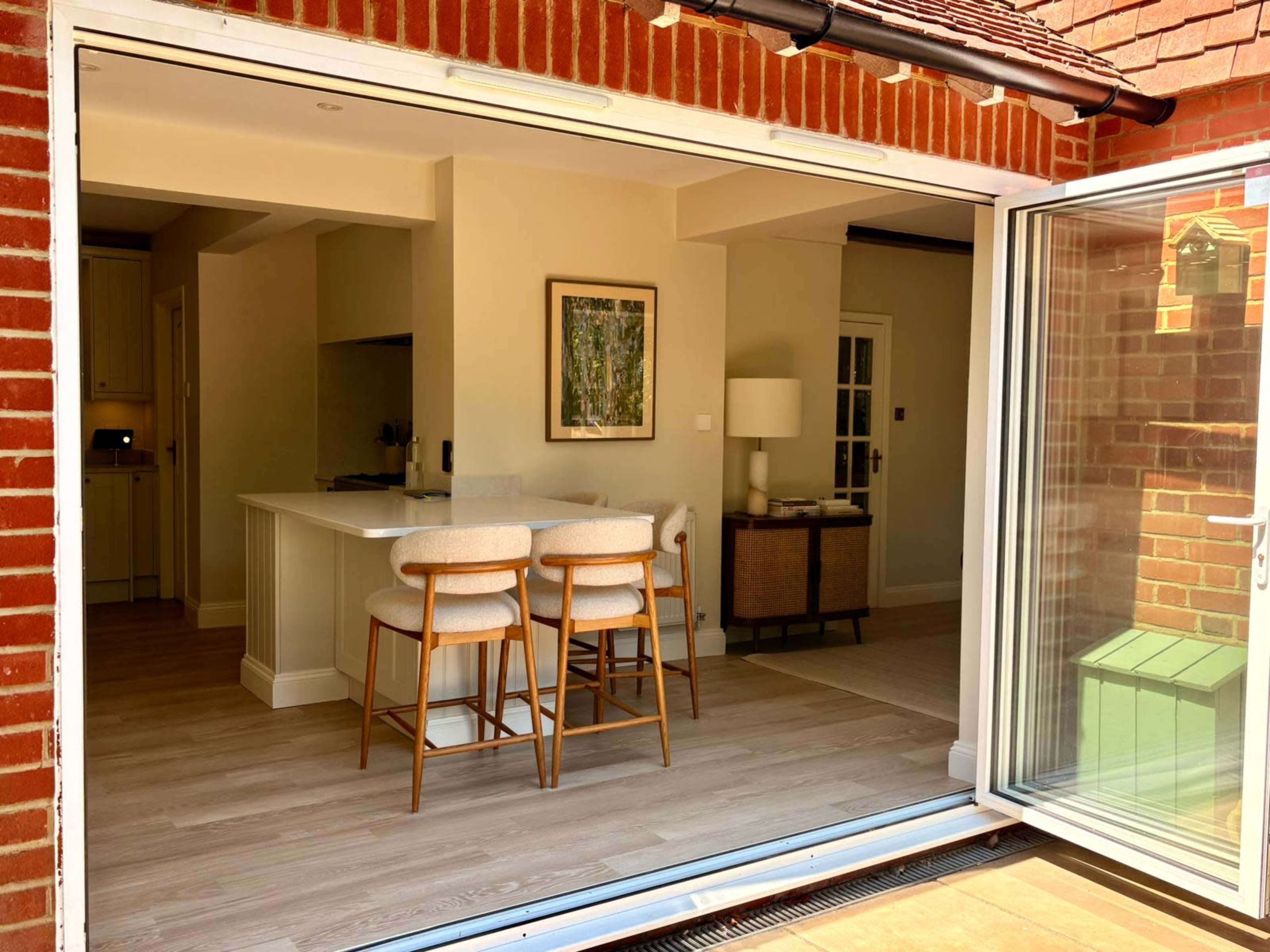 The image shows a modern, open-concept kitchen and living area with a sliding glass door leading to an outdoor space.