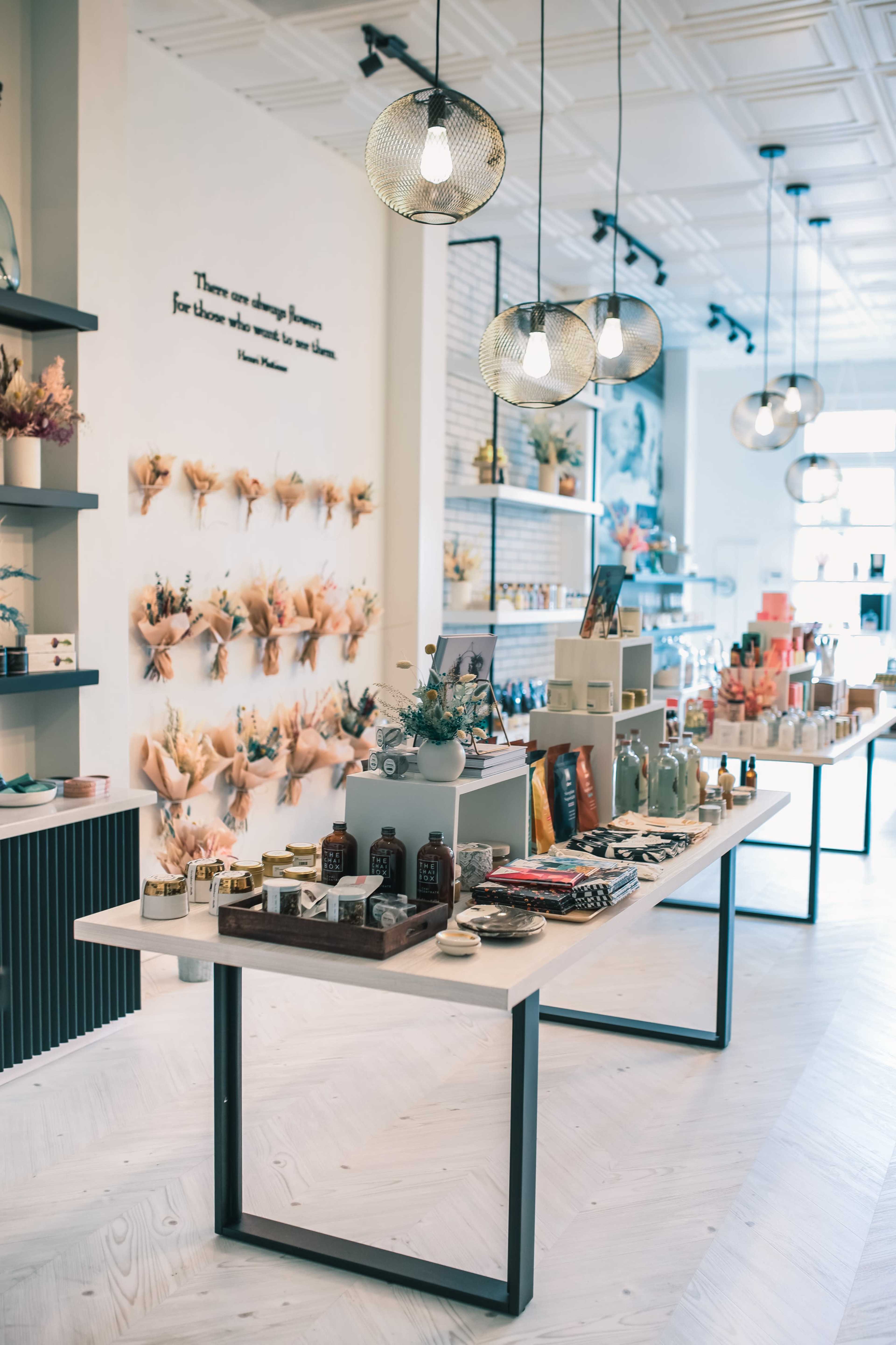 A modern retail store features neatly arranged shelves of products and a central display table under decorative pendant lights.