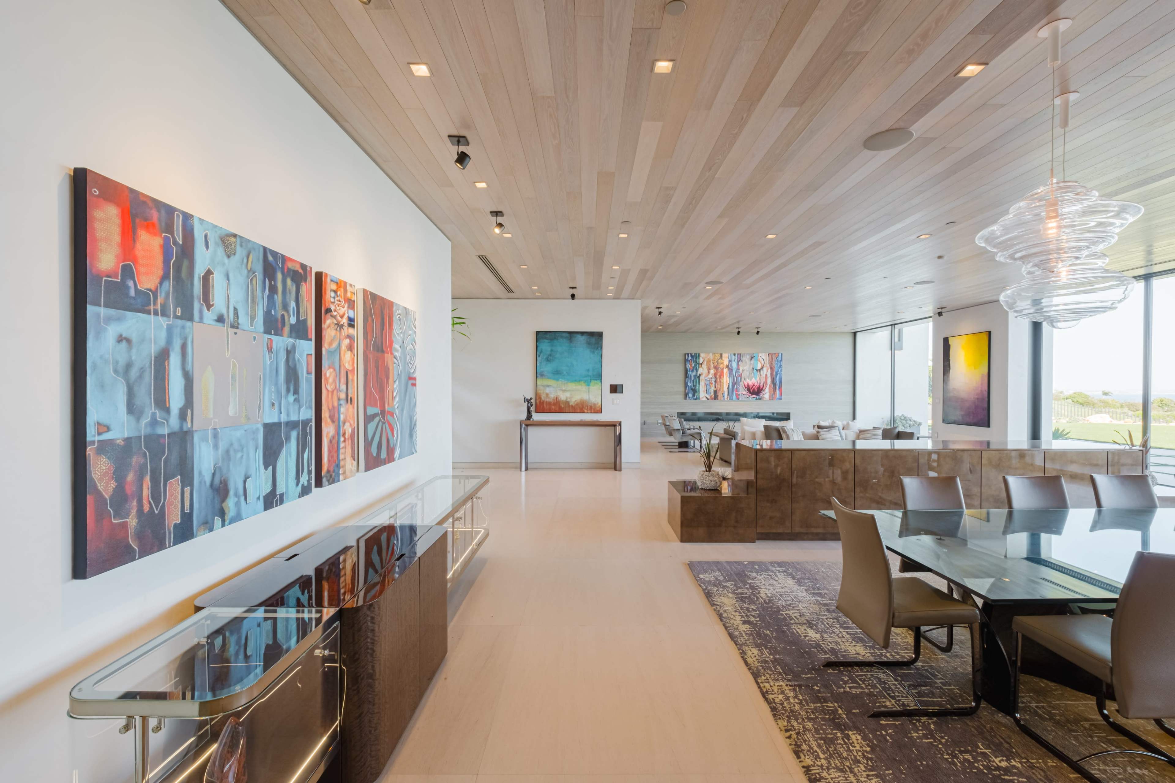 A modern interior with wooden ceilings, a dining area, and vibrant abstract artwork on the walls.
