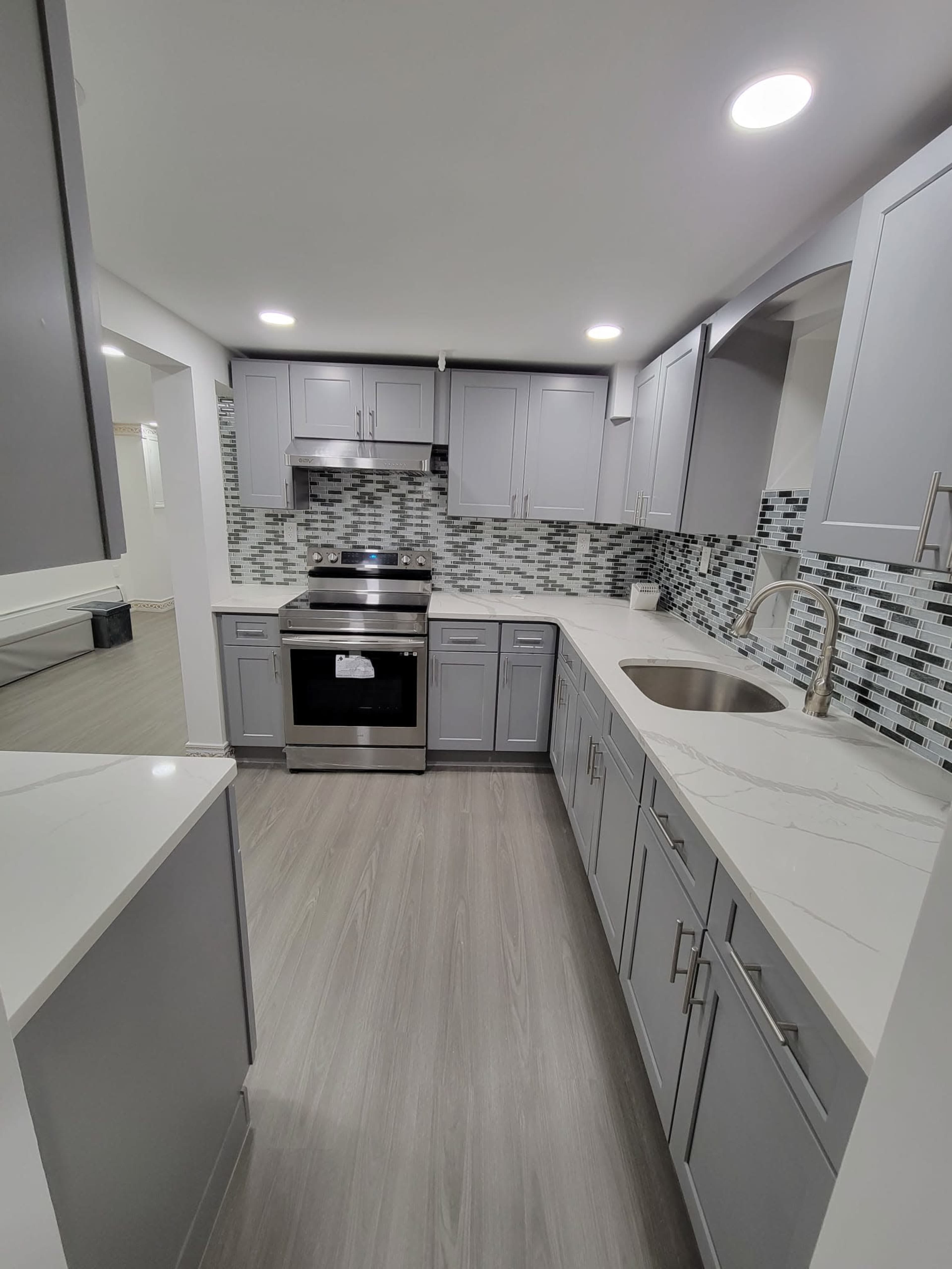 A modern kitchen with gray cabinets, a stainless steel stove, and a tiled backsplash.