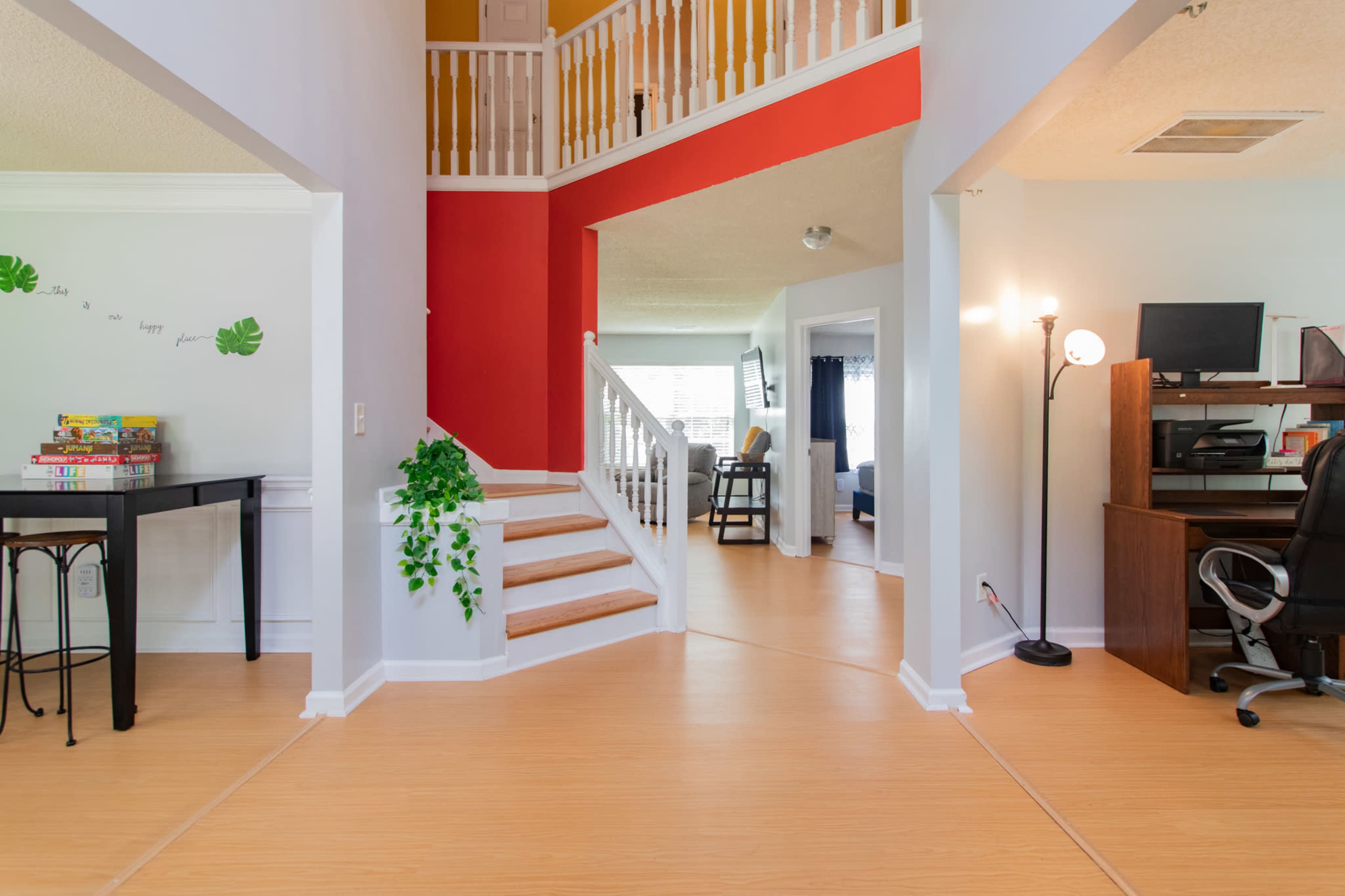 A spacious entryway features a staircase leading to an upper level and an open view into a living area with a desk and seating.
