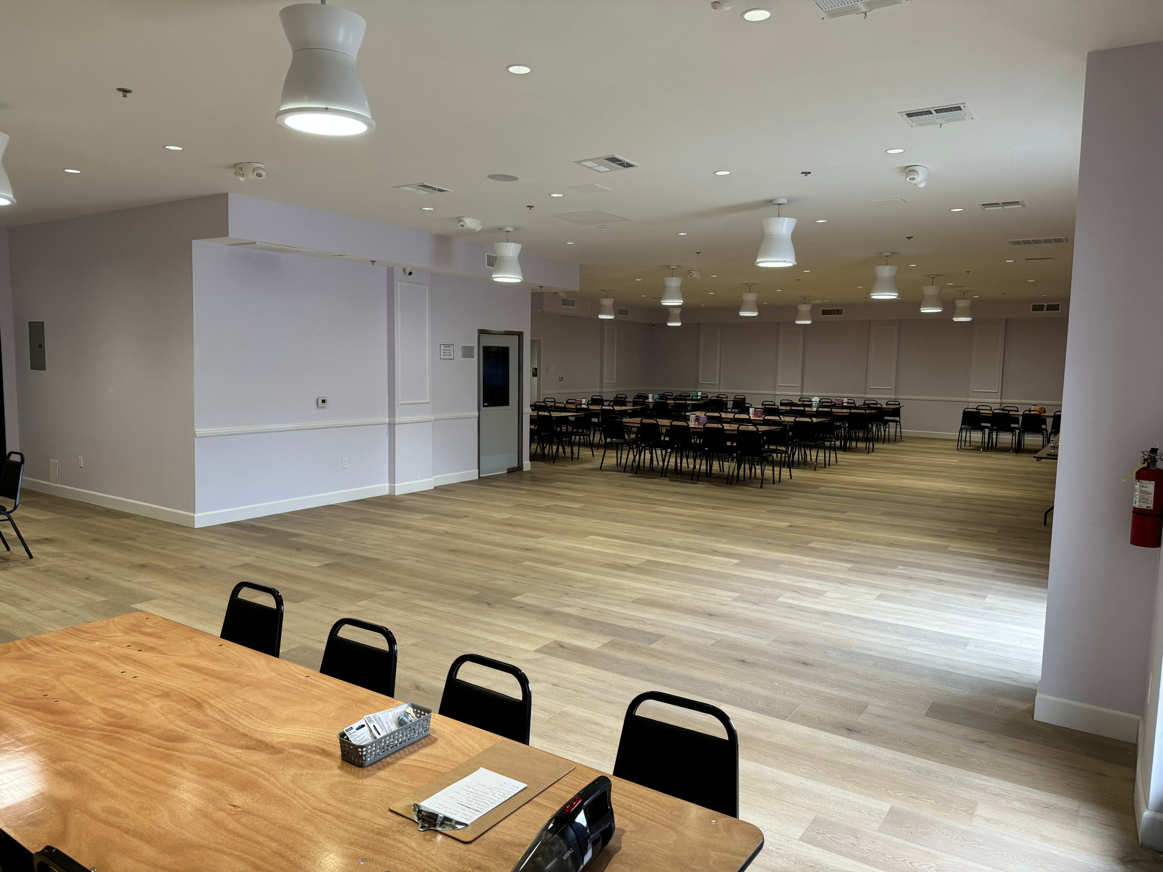 A spacious, well-lit banquet hall with rows of empty tables and chairs set up for an event.